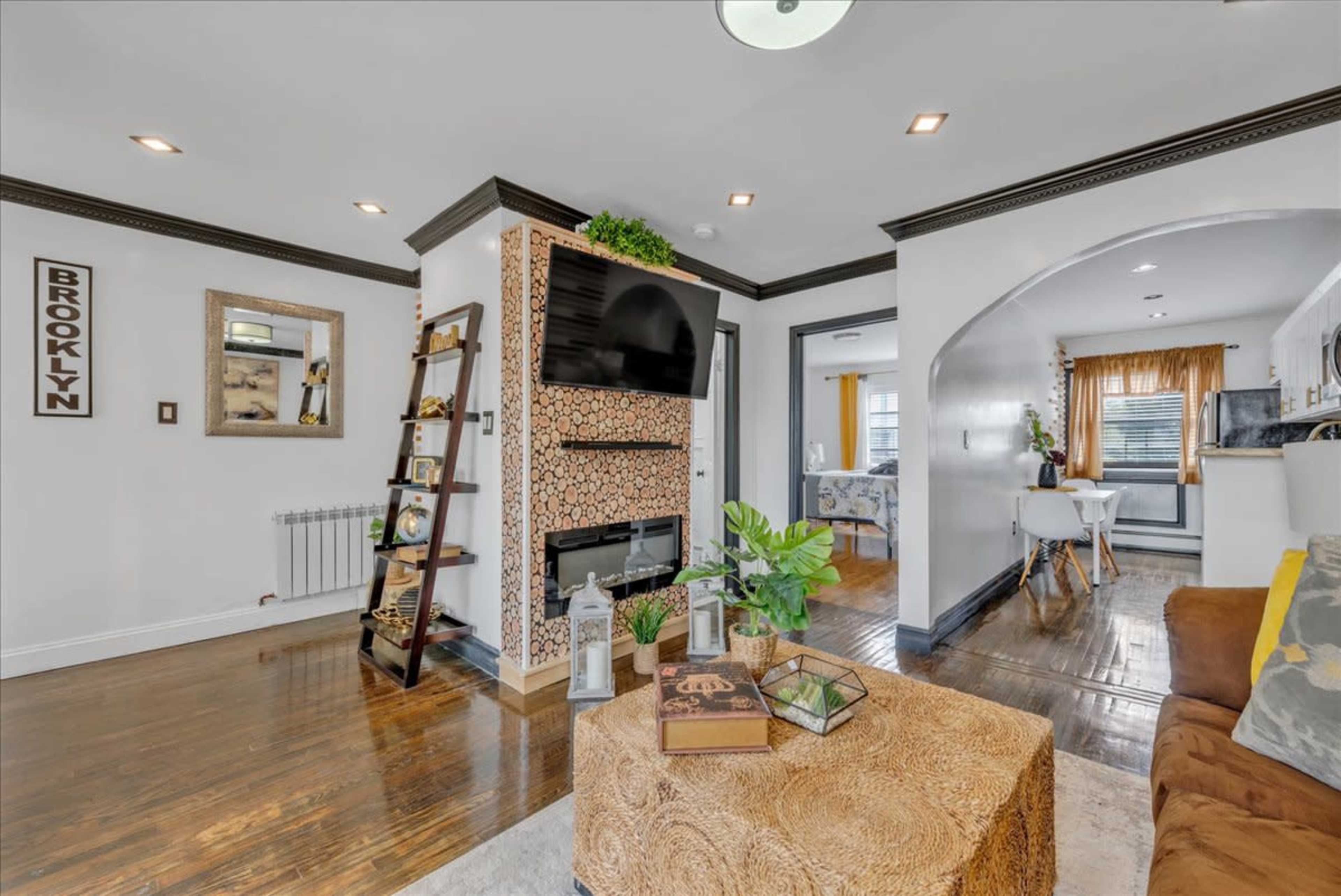 A modern living room with a decorative fireplace, a ladder bookshelf, and a cozy seating area adorned with plants and a coffee table.