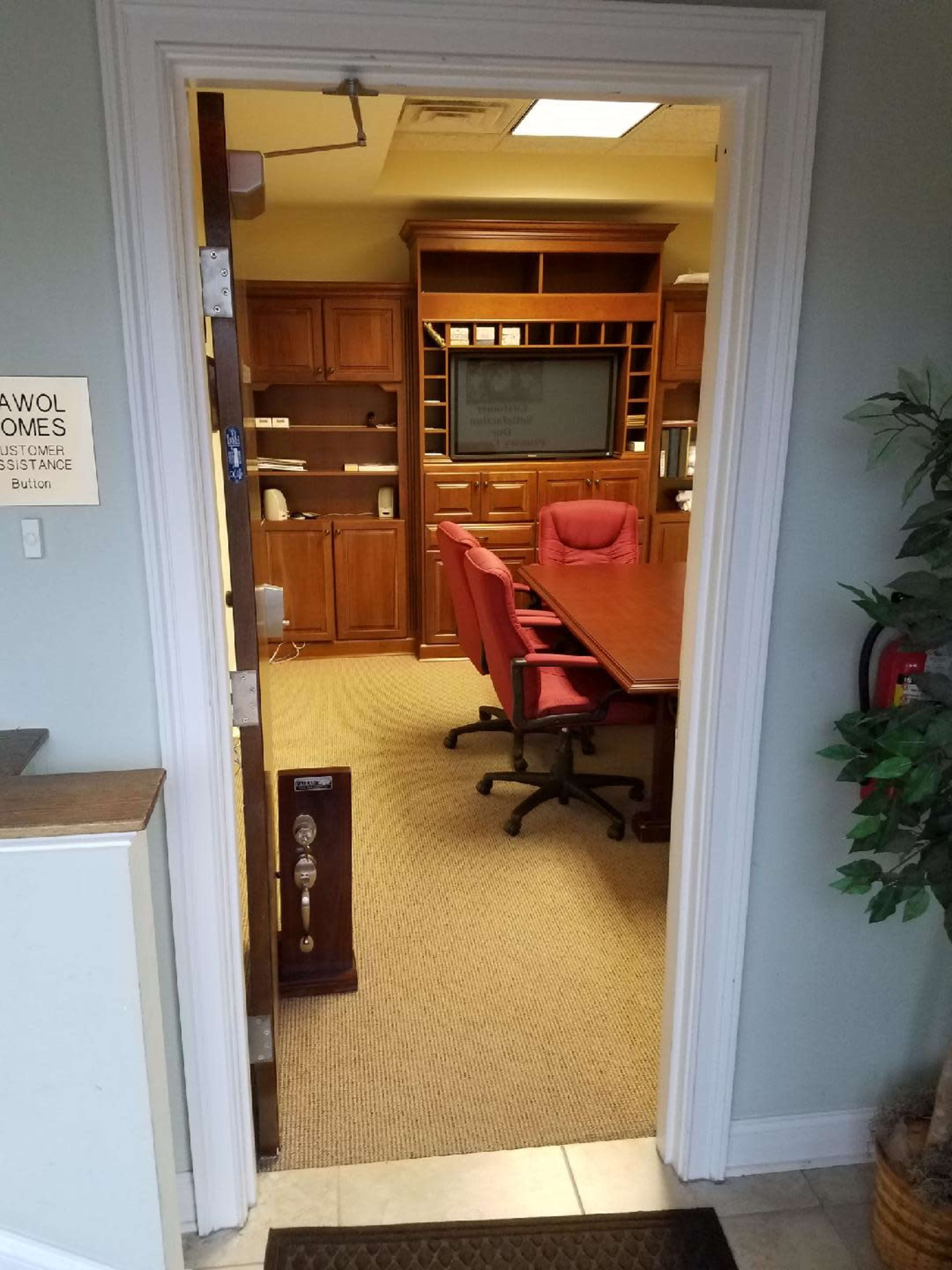 A conference room with a wooden table and red chairs is visible through an open doorway.