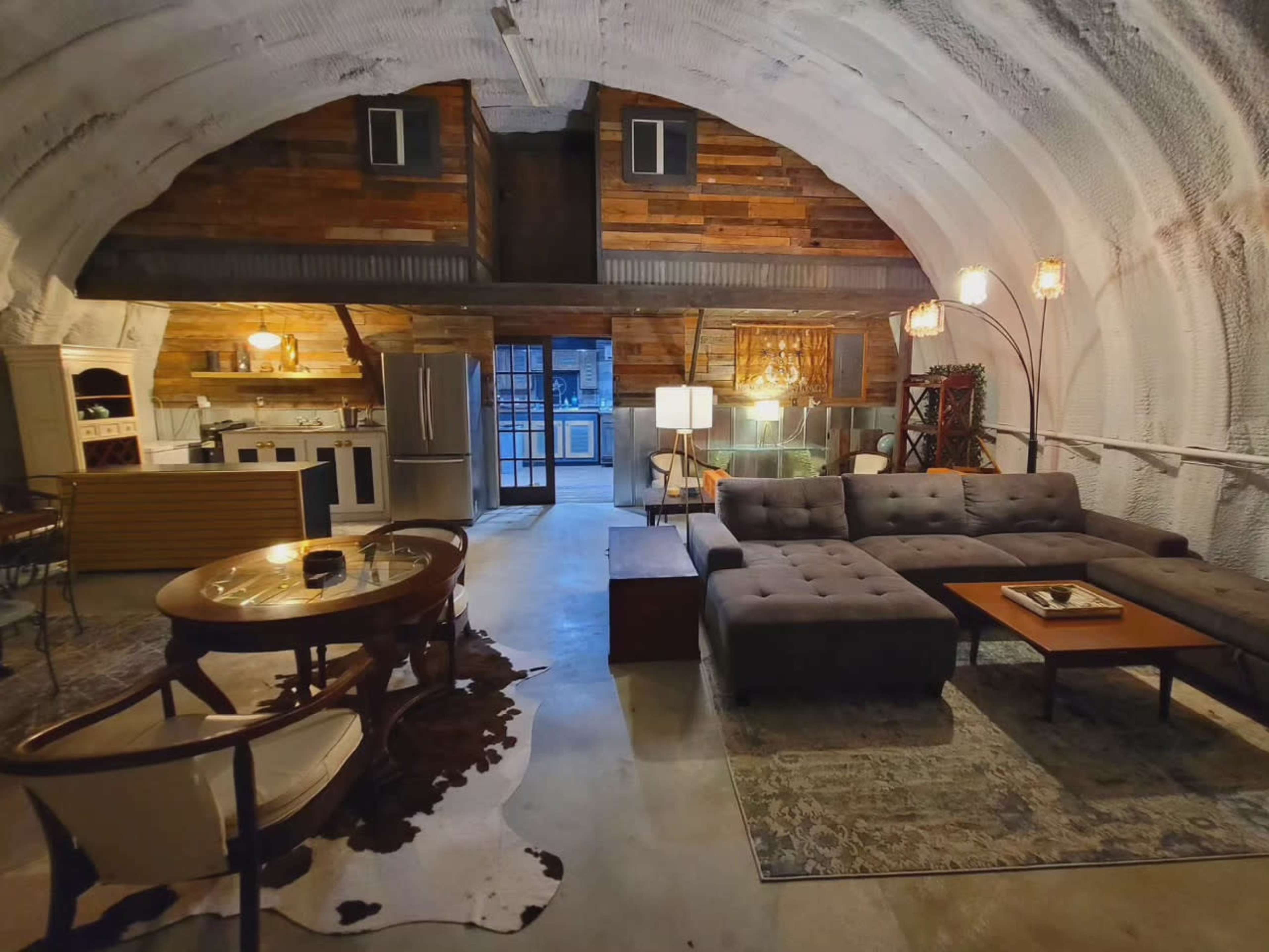 A spacious, modern living area with an arched ceiling, featuring a kitchen, dining area, and a sectional sofa.