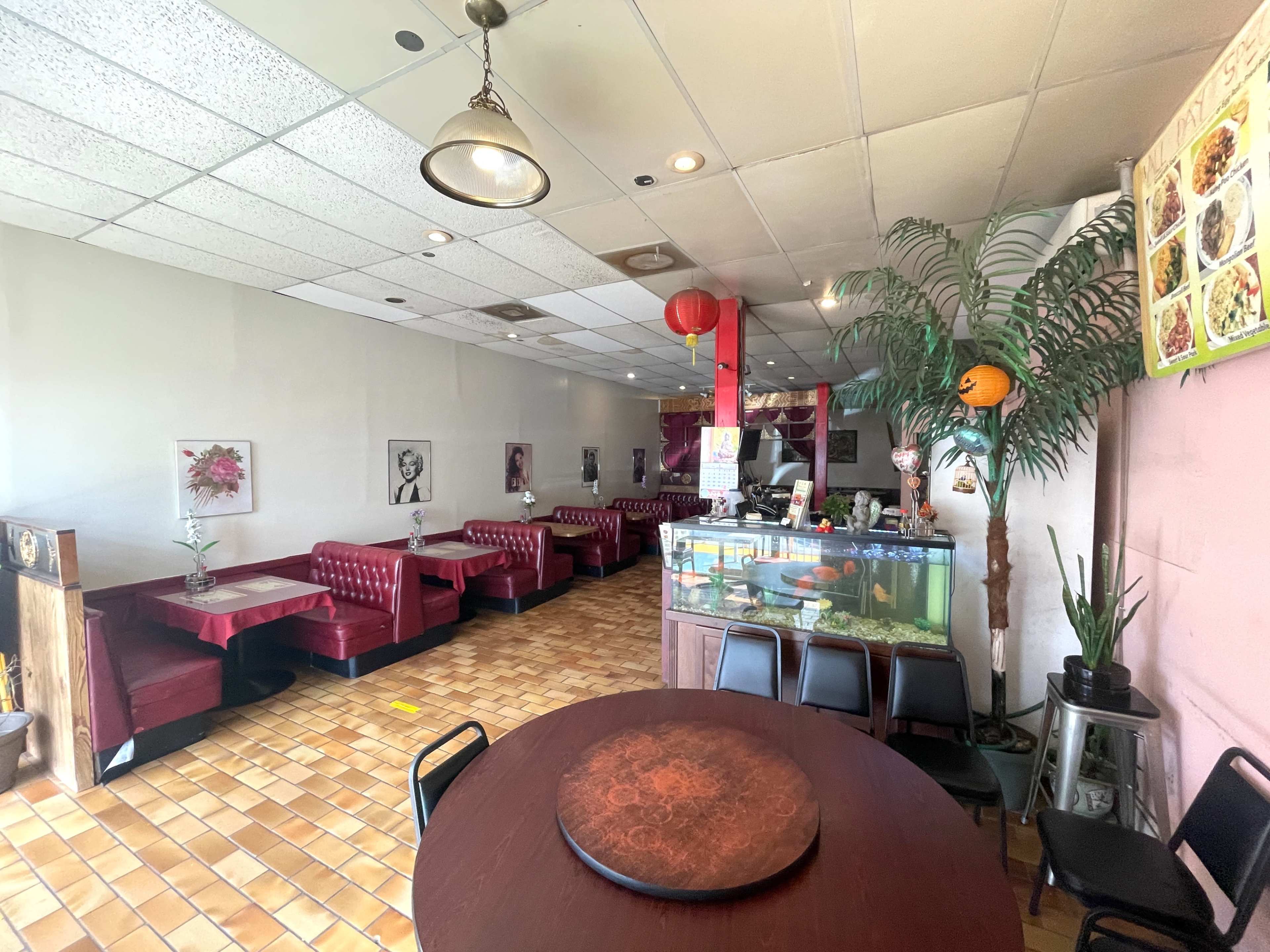 The image shows the interior of a restaurant featuring red booth seating, a fish tank, and a dining area with round tables.