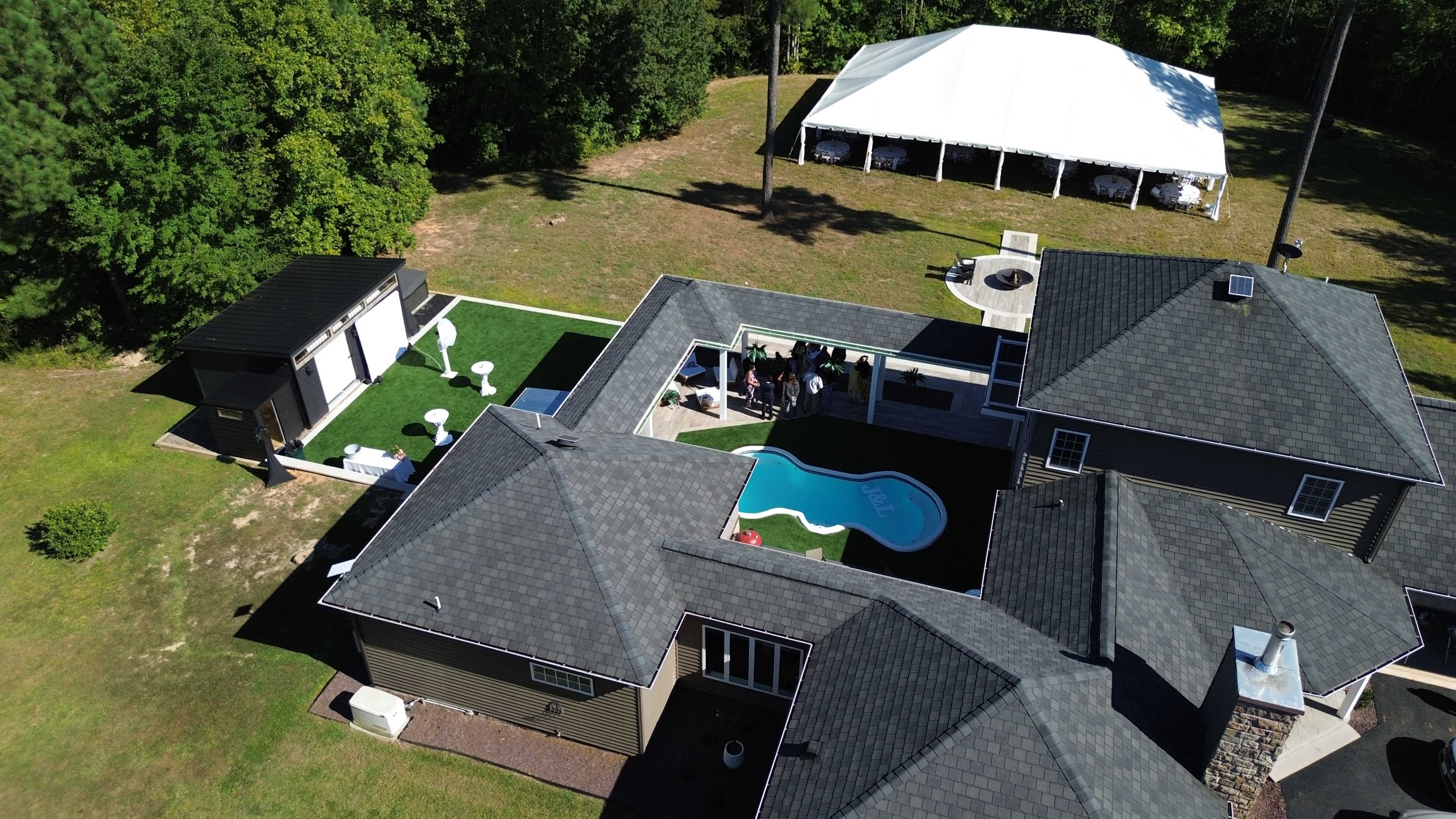 An aerial view shows a modern house with a pool and a large tent set up in the backyard.