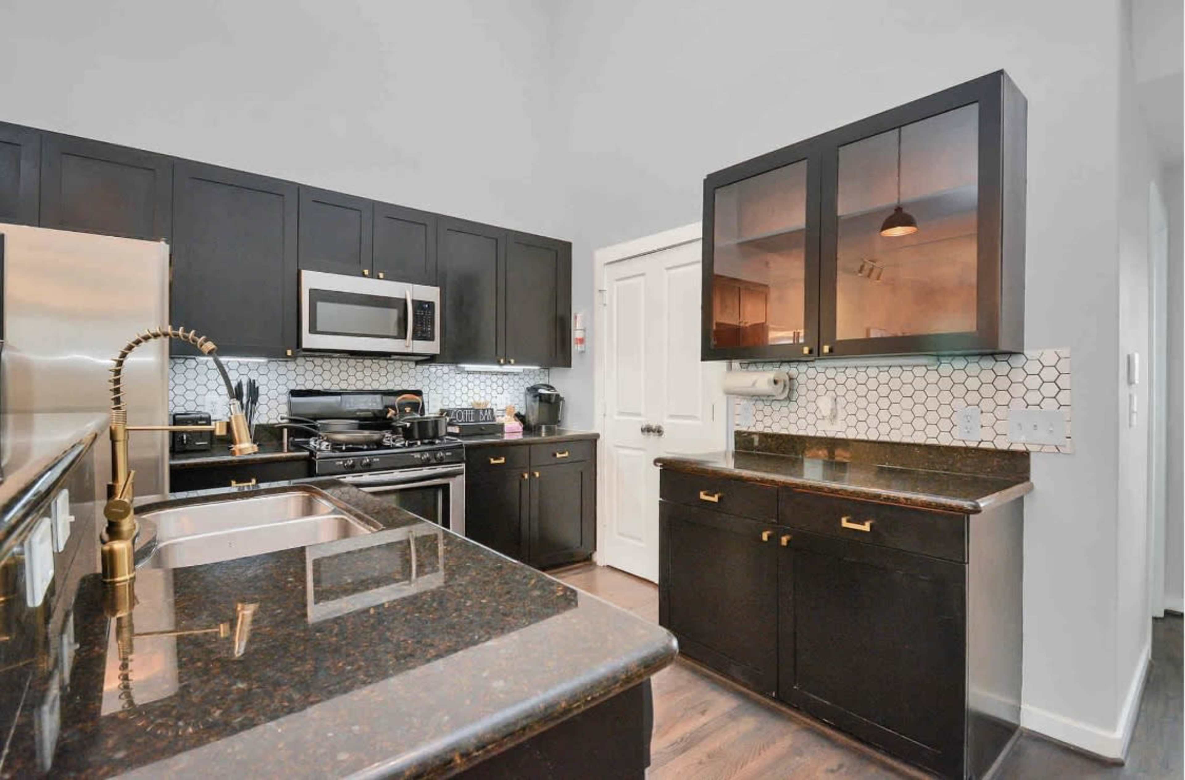 The kitchen features dark cabinetry, a stainless steel refrigerator, and a countertop with a hexagonal backsplash.