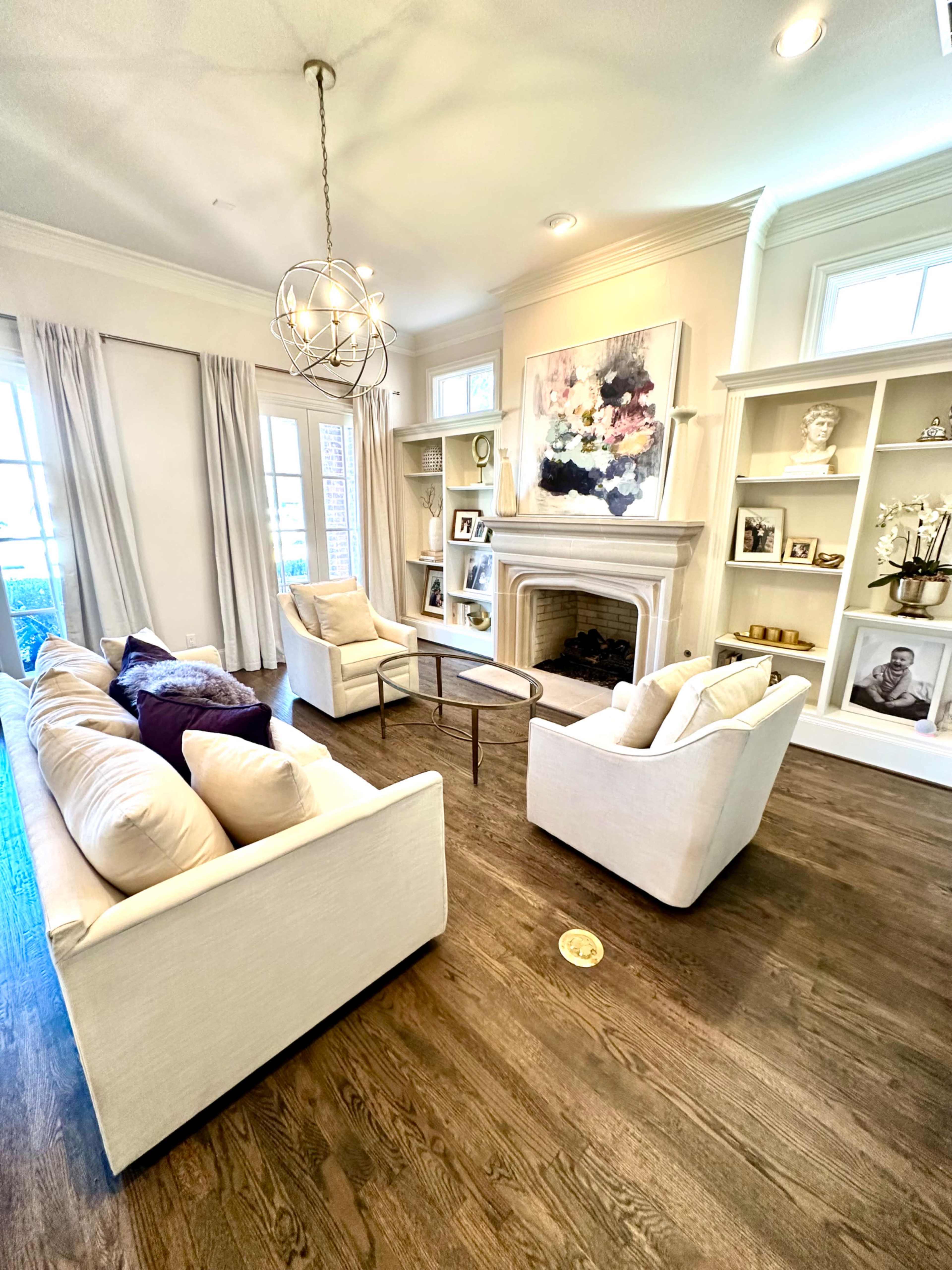 A living room featuring a light-colored sofa set arranged around a small coffee table, with built-in shelves displaying decorative items and artwork.