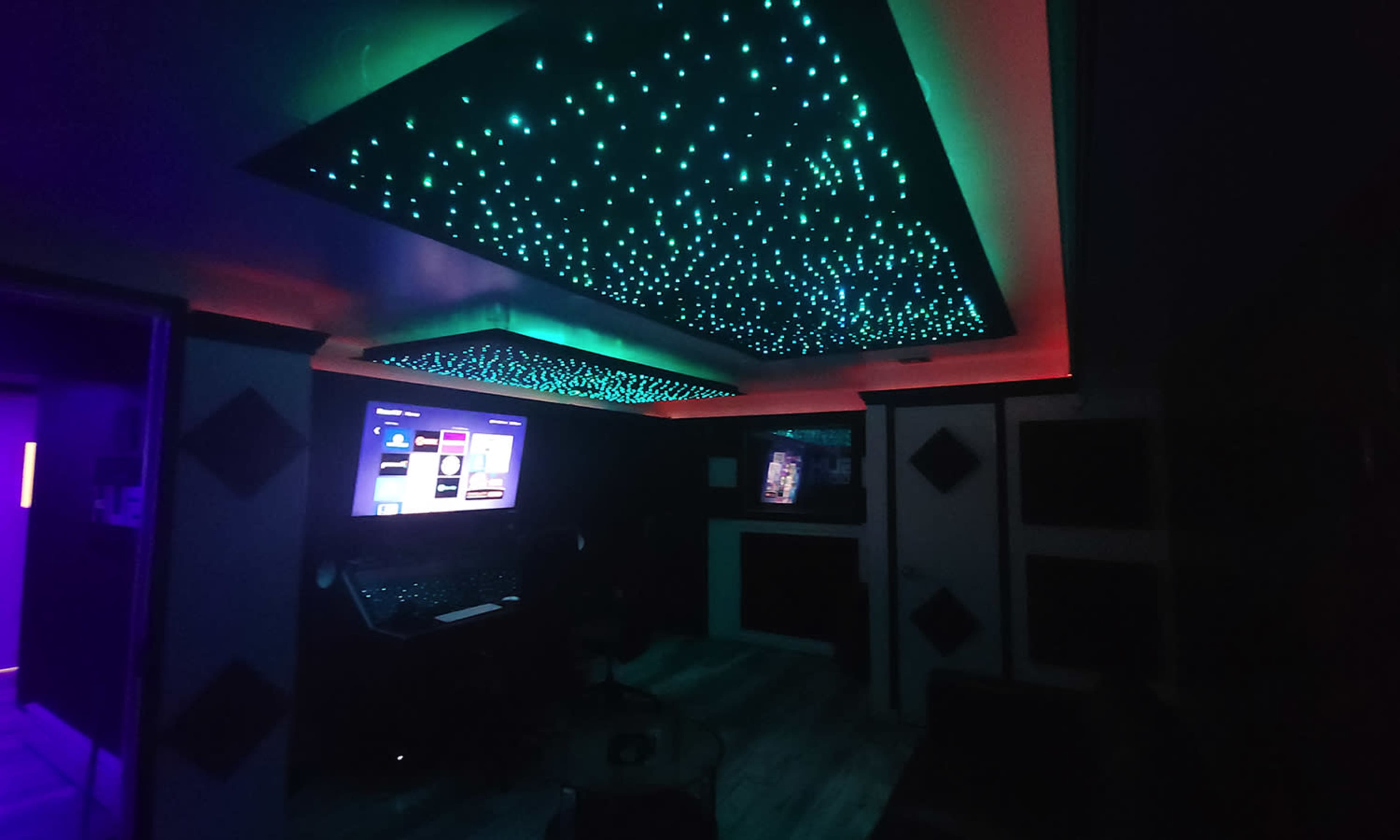 A dark room with a starry ceiling of LED lights and a large screen displaying a user interface.