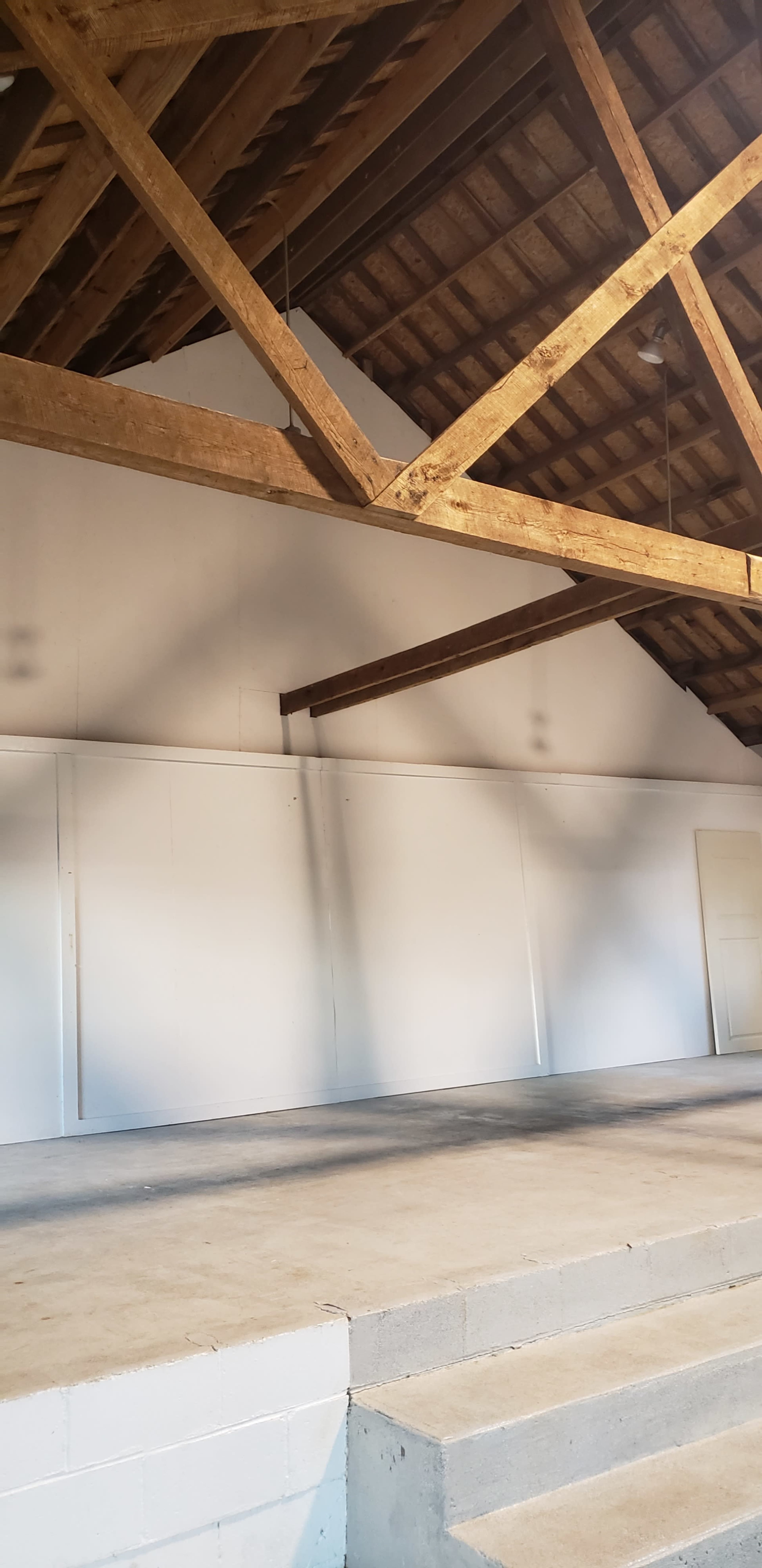 A spacious interior with white walls and exposed wooden beams on the ceiling.