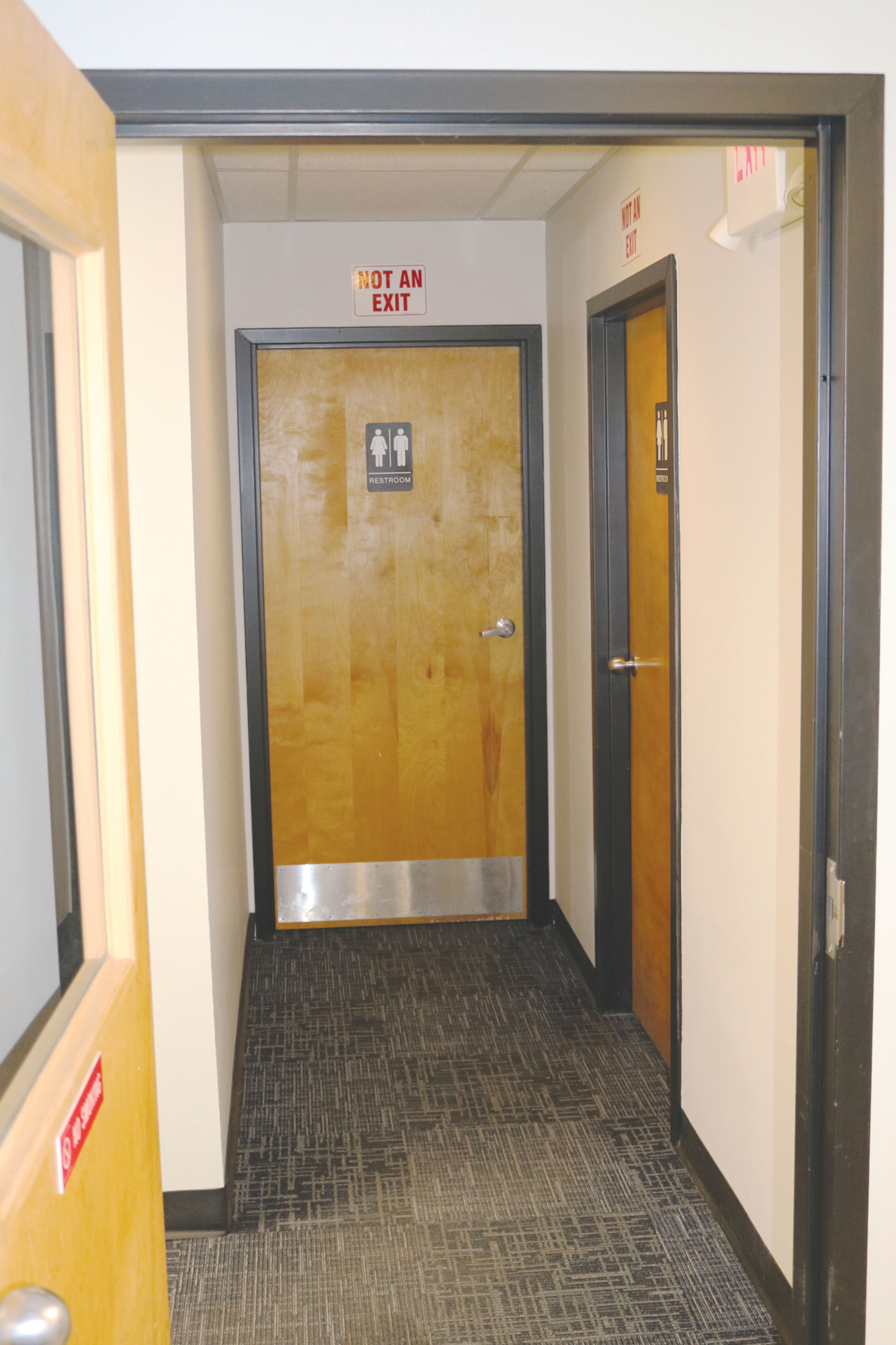 A hallway features two doors, one labeled for restrooms and the other marked with a "NOT AN EXIT" sign.