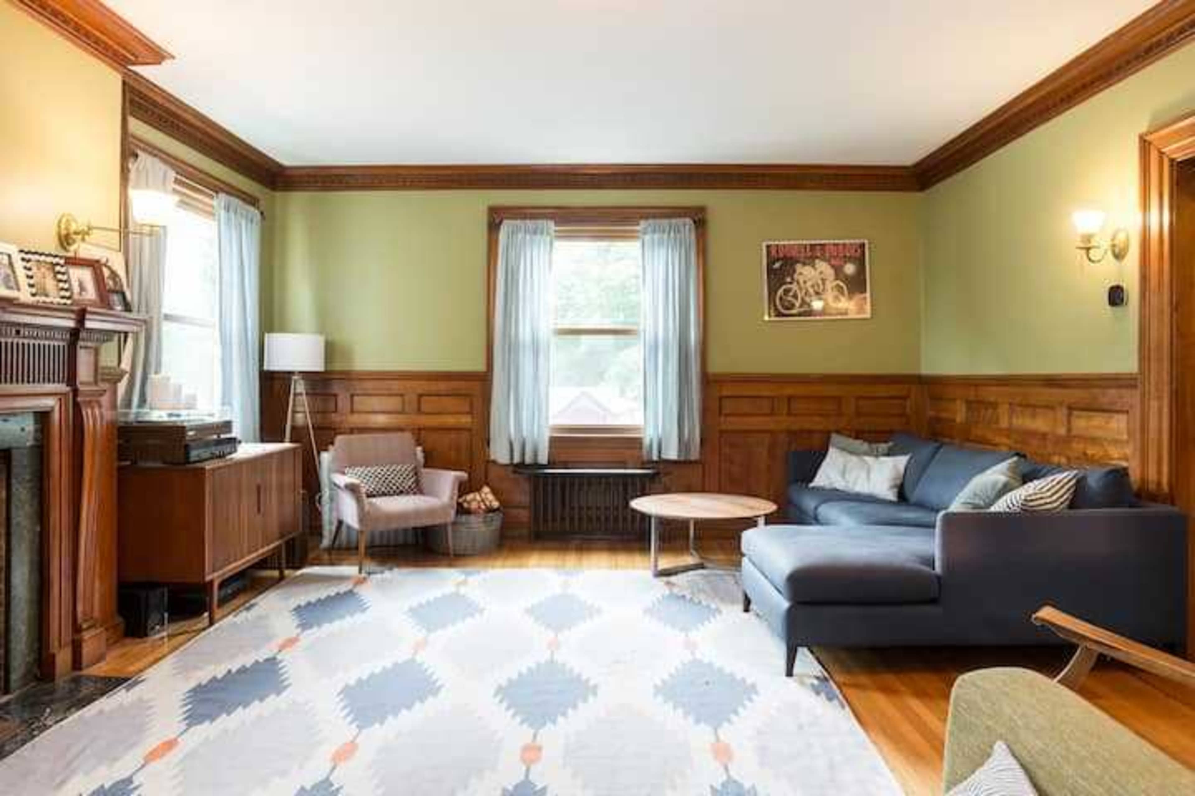 A living room with a sofa, coffee table, and a combination of wooden paneling and light-colored walls.