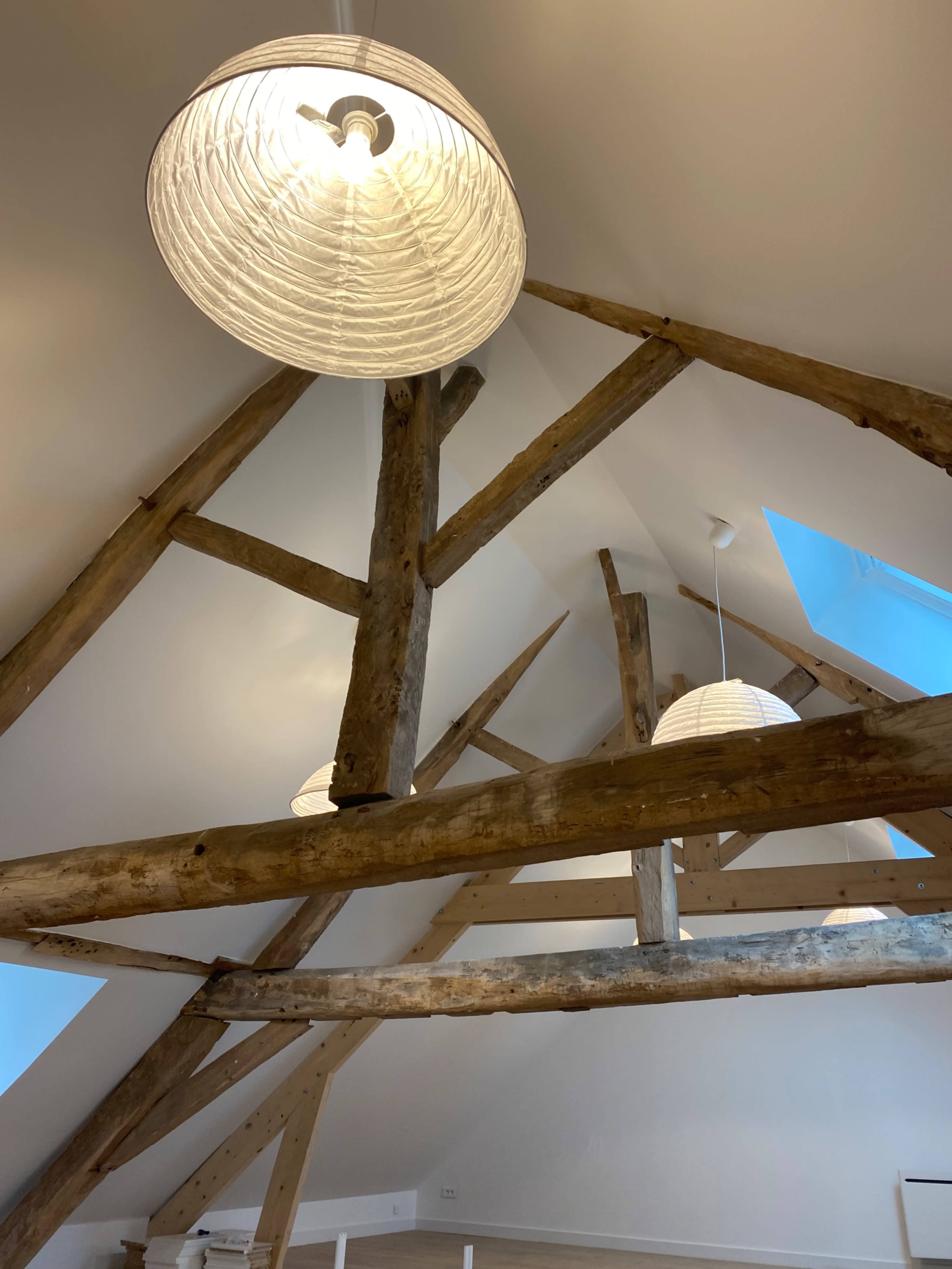 The image shows a room with exposed wooden beams and two pendant lights hanging from the ceiling.