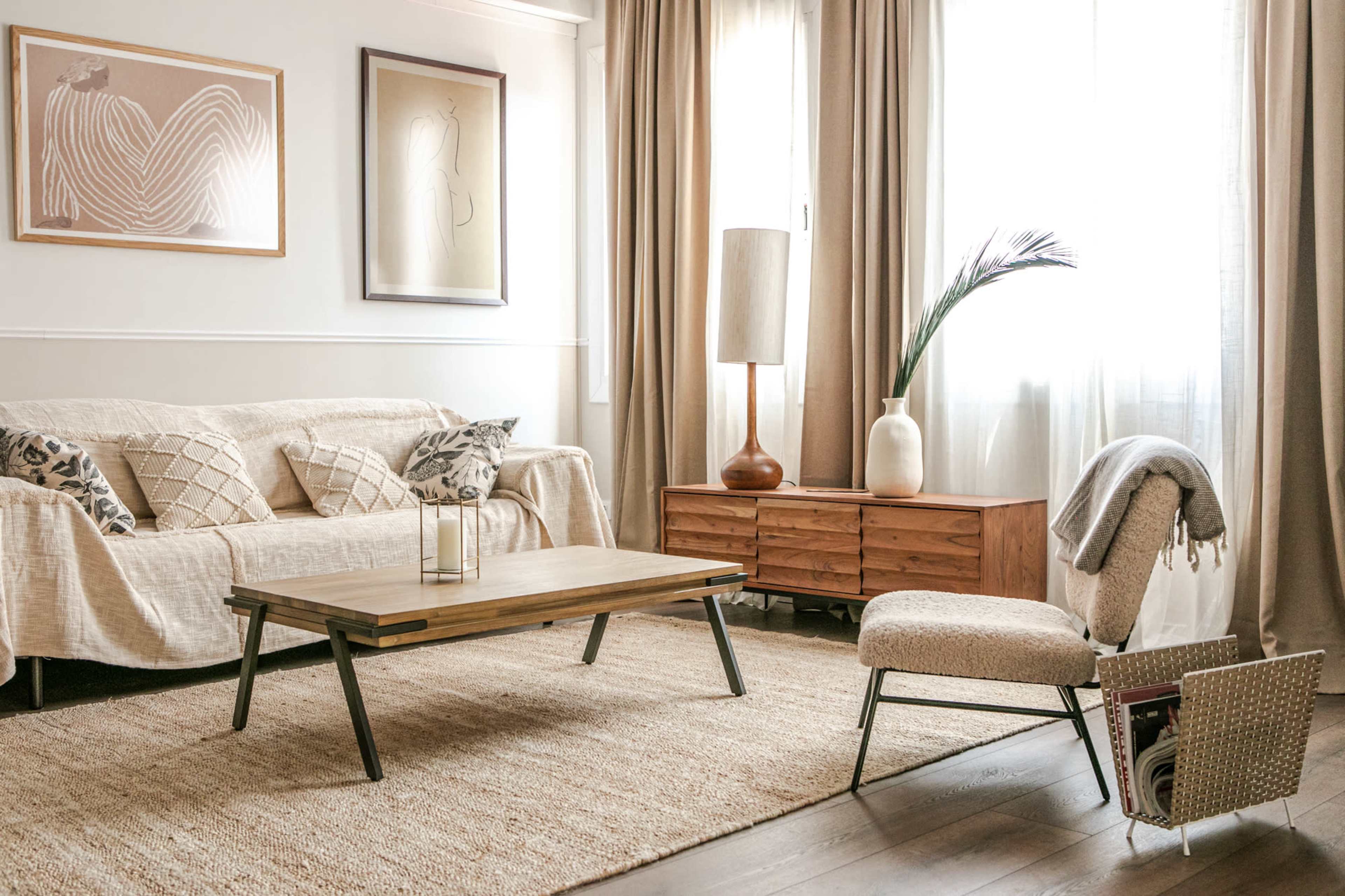 A cozy living room featuring a sofa with decorative pillows, a wooden coffee table, a tall lamp, and a chair beside a storage basket.