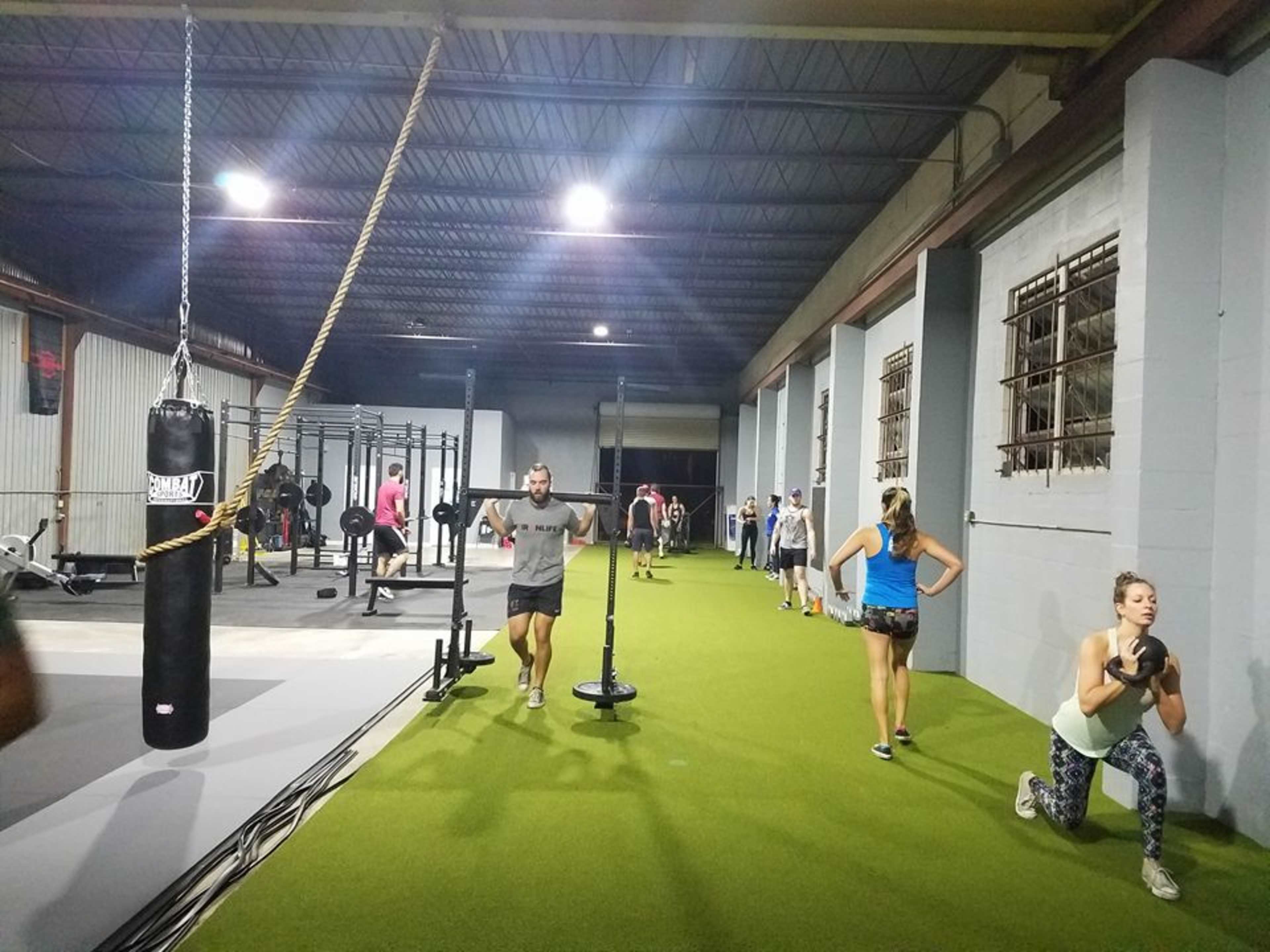 A diverse group of people is exercising in a spacious indoor gym equipped with various workout stations and fitness equipment.