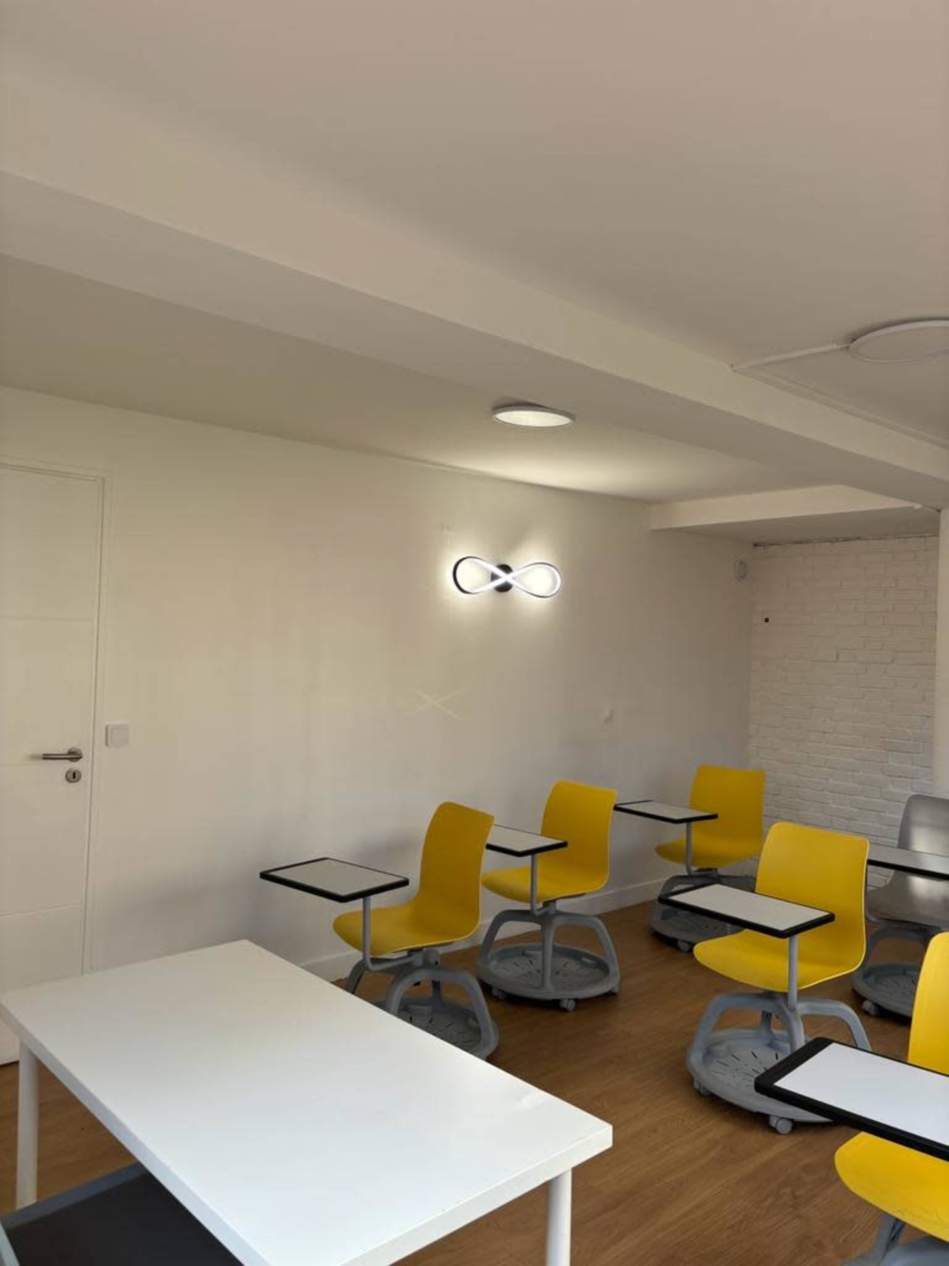 A modern classroom with yellow chairs and desks arranged in a minimalist design.