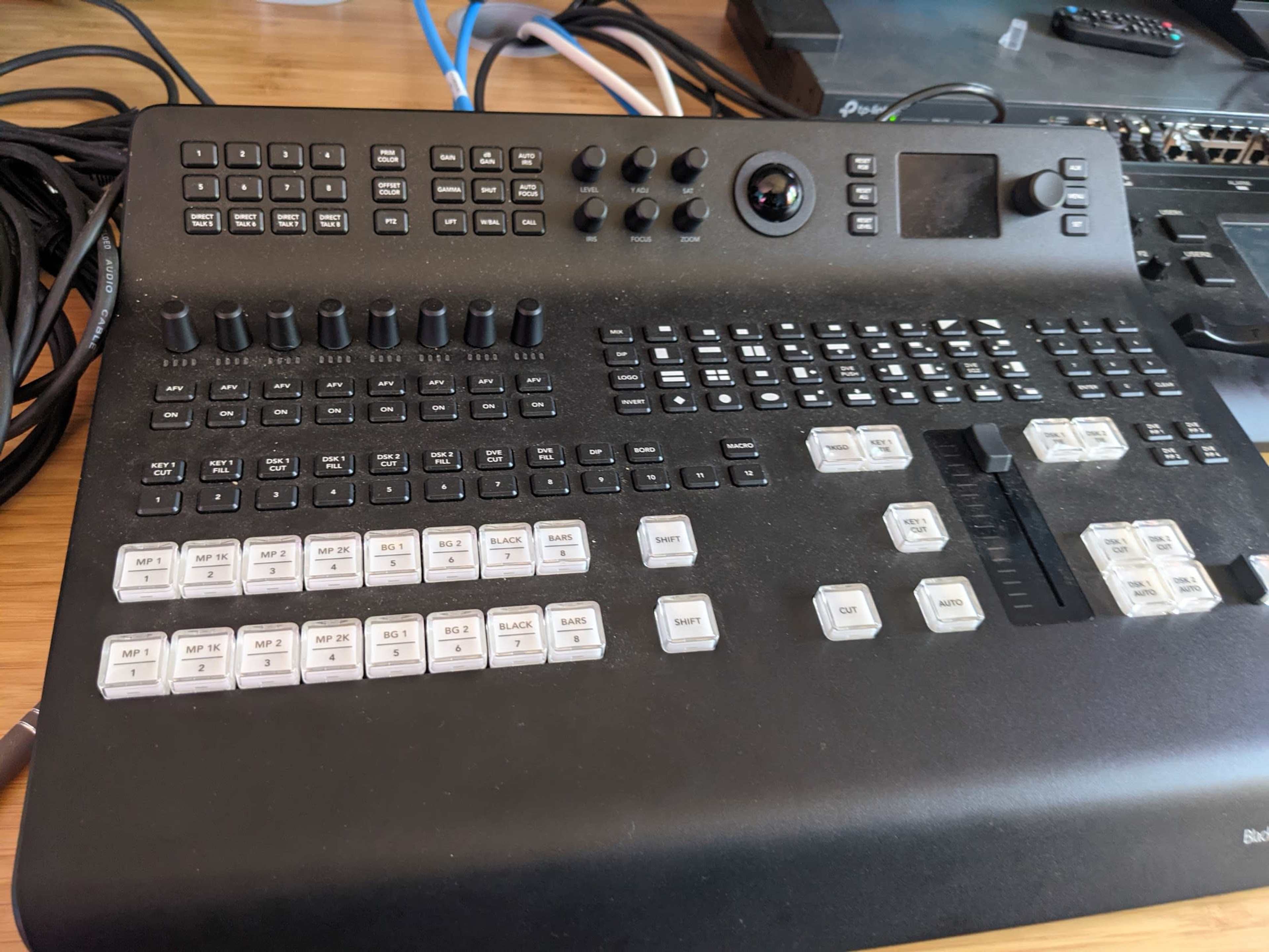 A black video switcher control panel with various buttons, dials, and sliders.