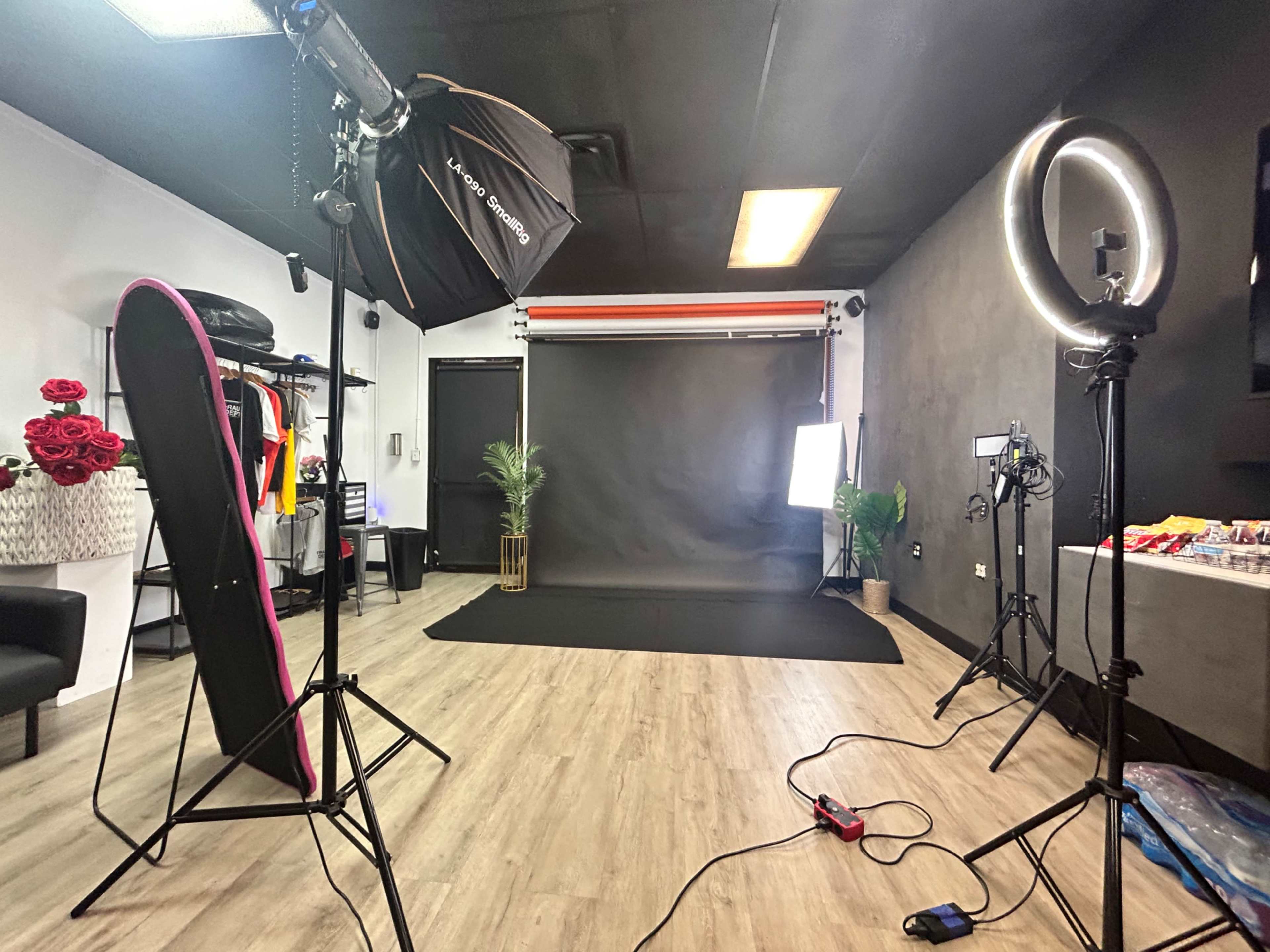 The image shows a photography studio setup with various lighting equipment, a backdrop, and a seating area.