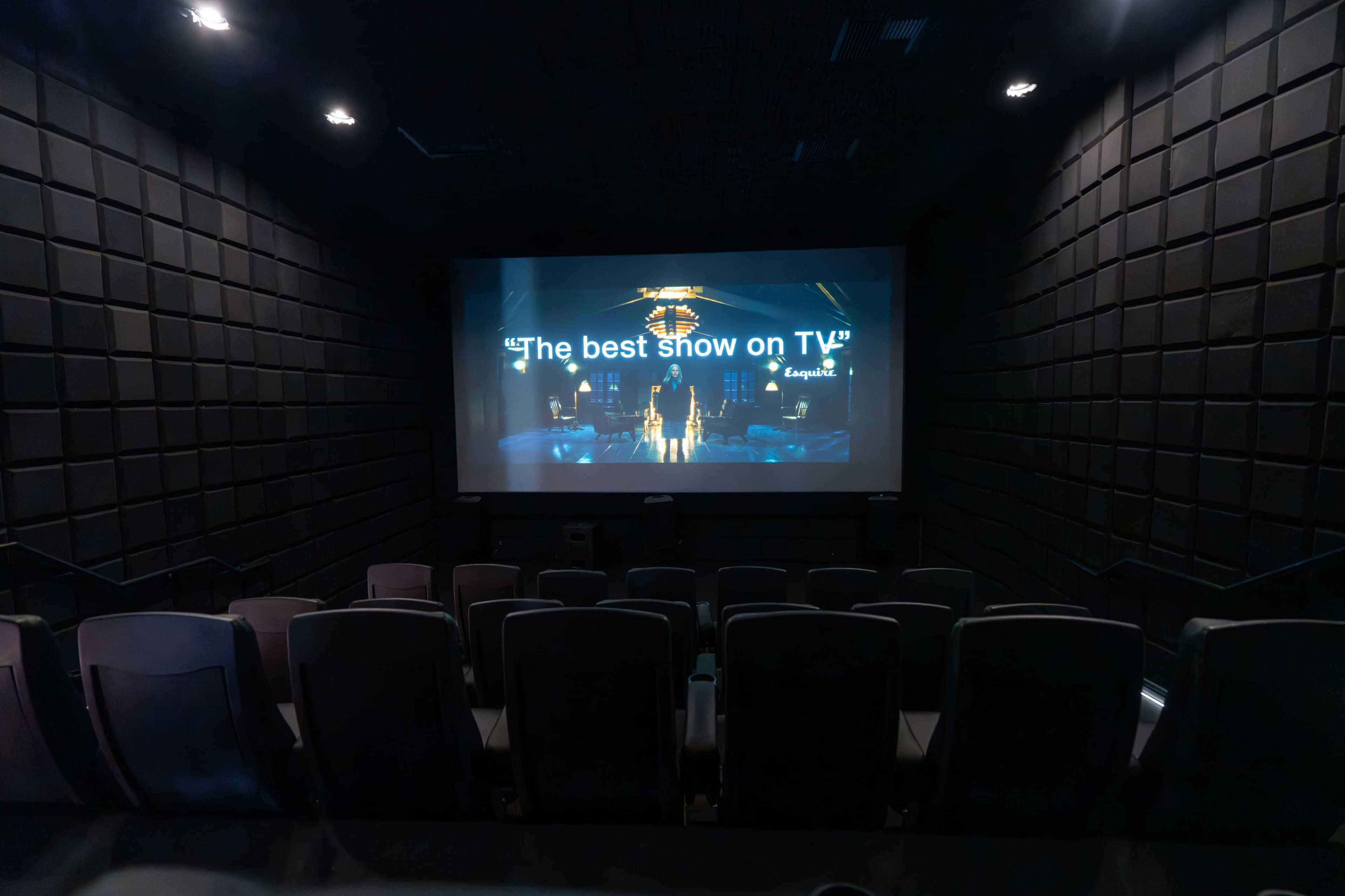 The image shows an empty movie theater with a large screen displaying the text "The best show on TV."