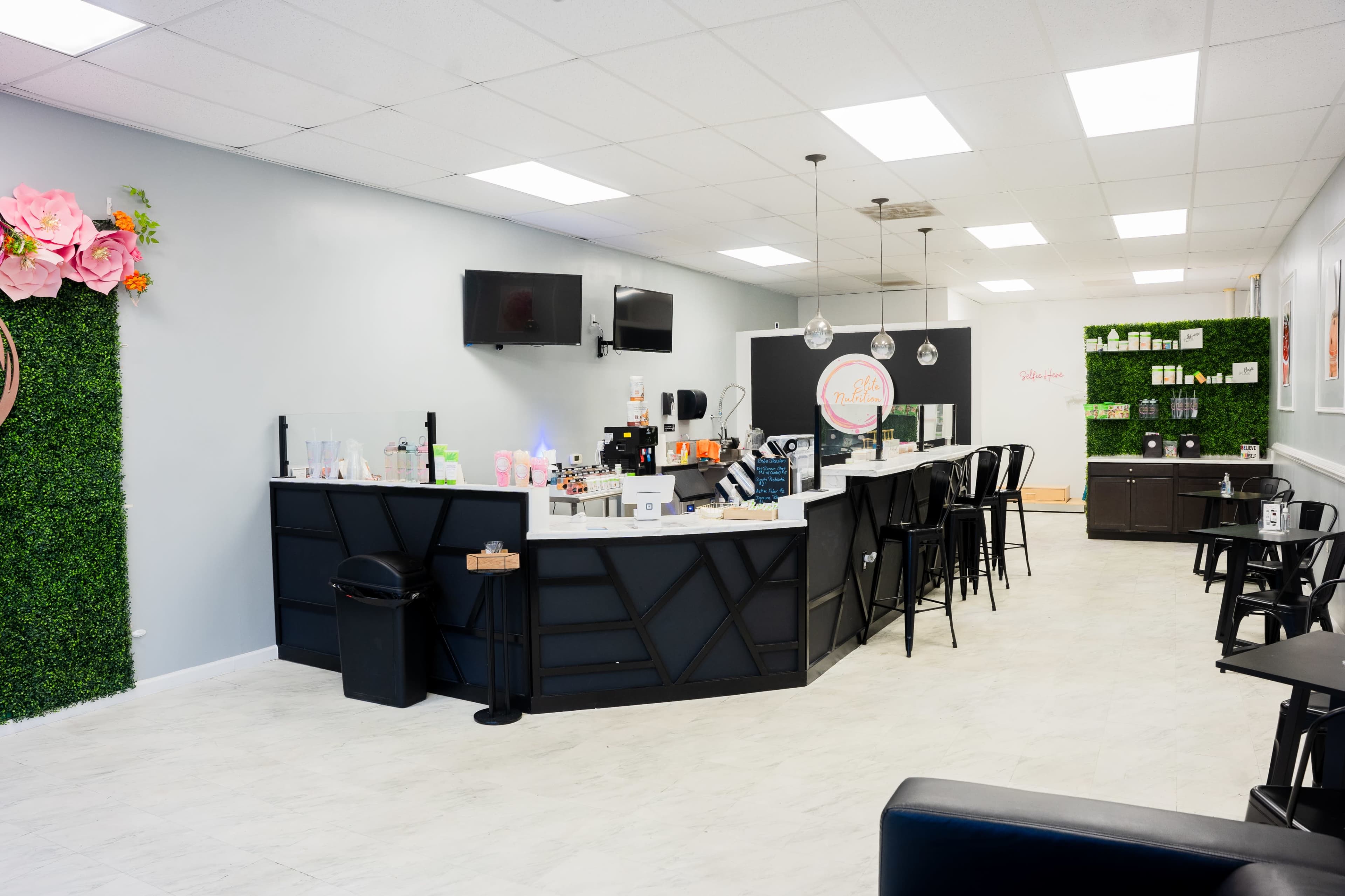 The image shows a modern spa interior with a reception desk, seating area, and products displayed on the walls.