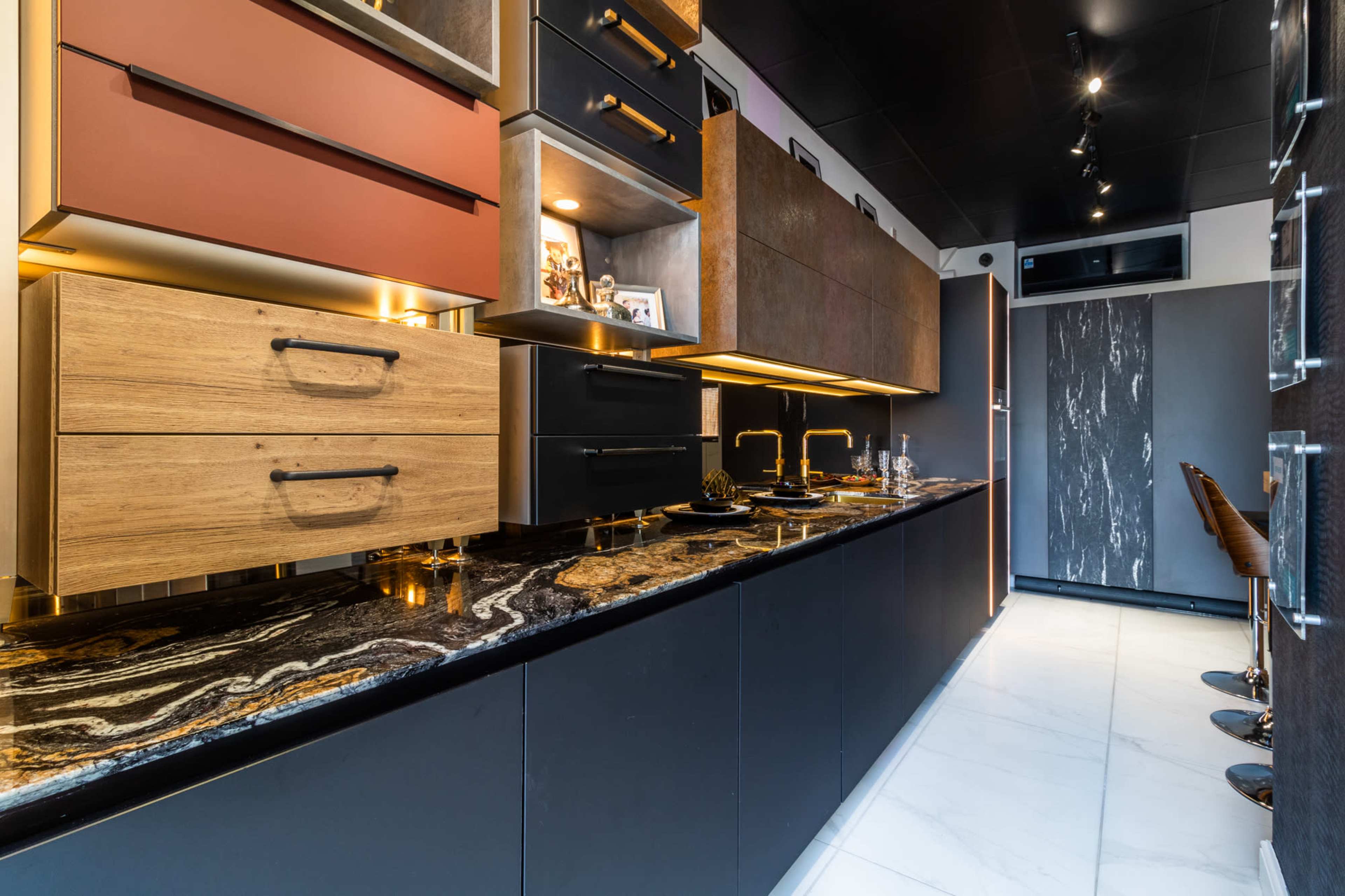 A modern kitchen features dark cabinets, a textured countertop with intricate patterns, and a minimalist design.