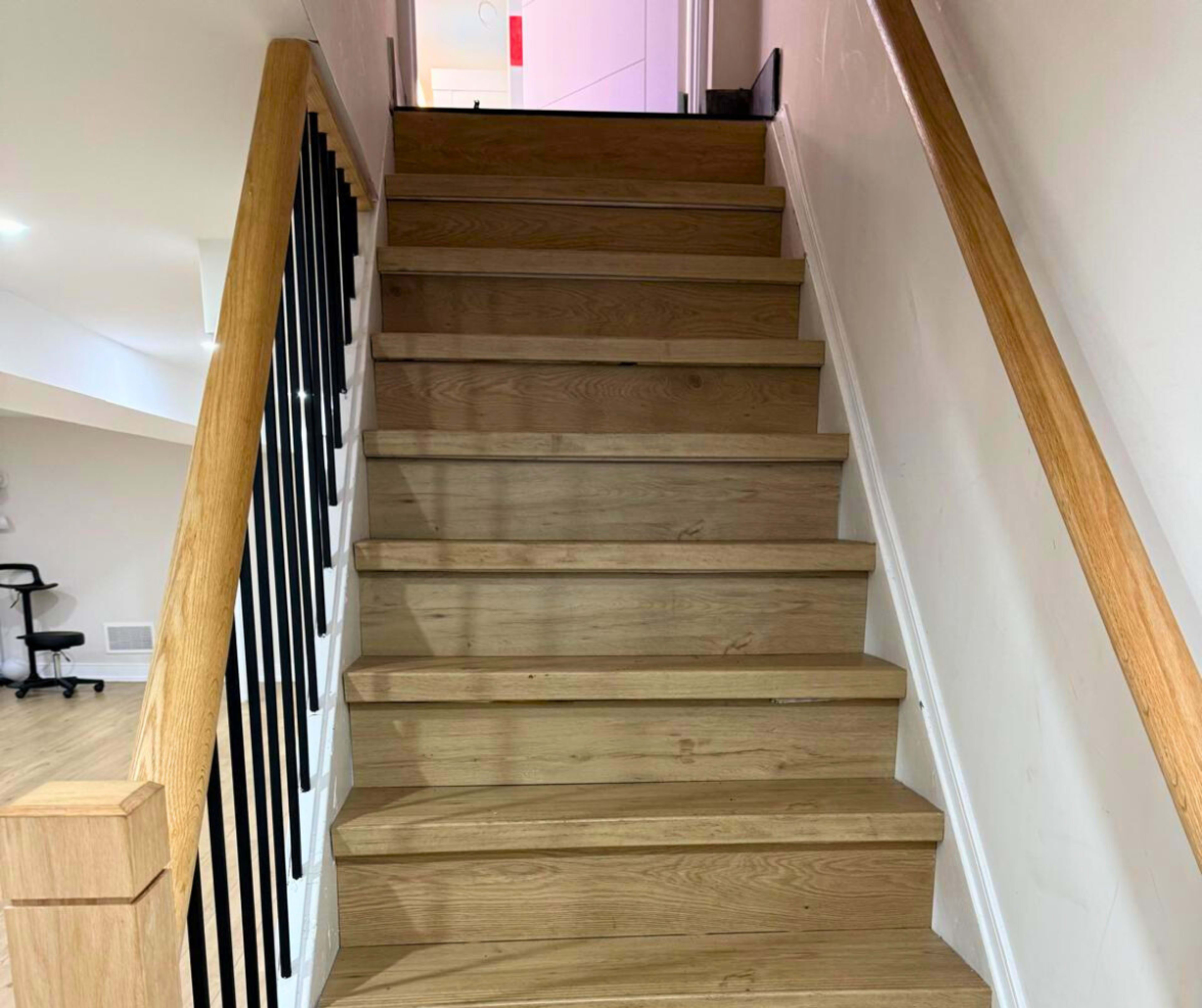 The image shows a wooden staircase with a railing leading upward.