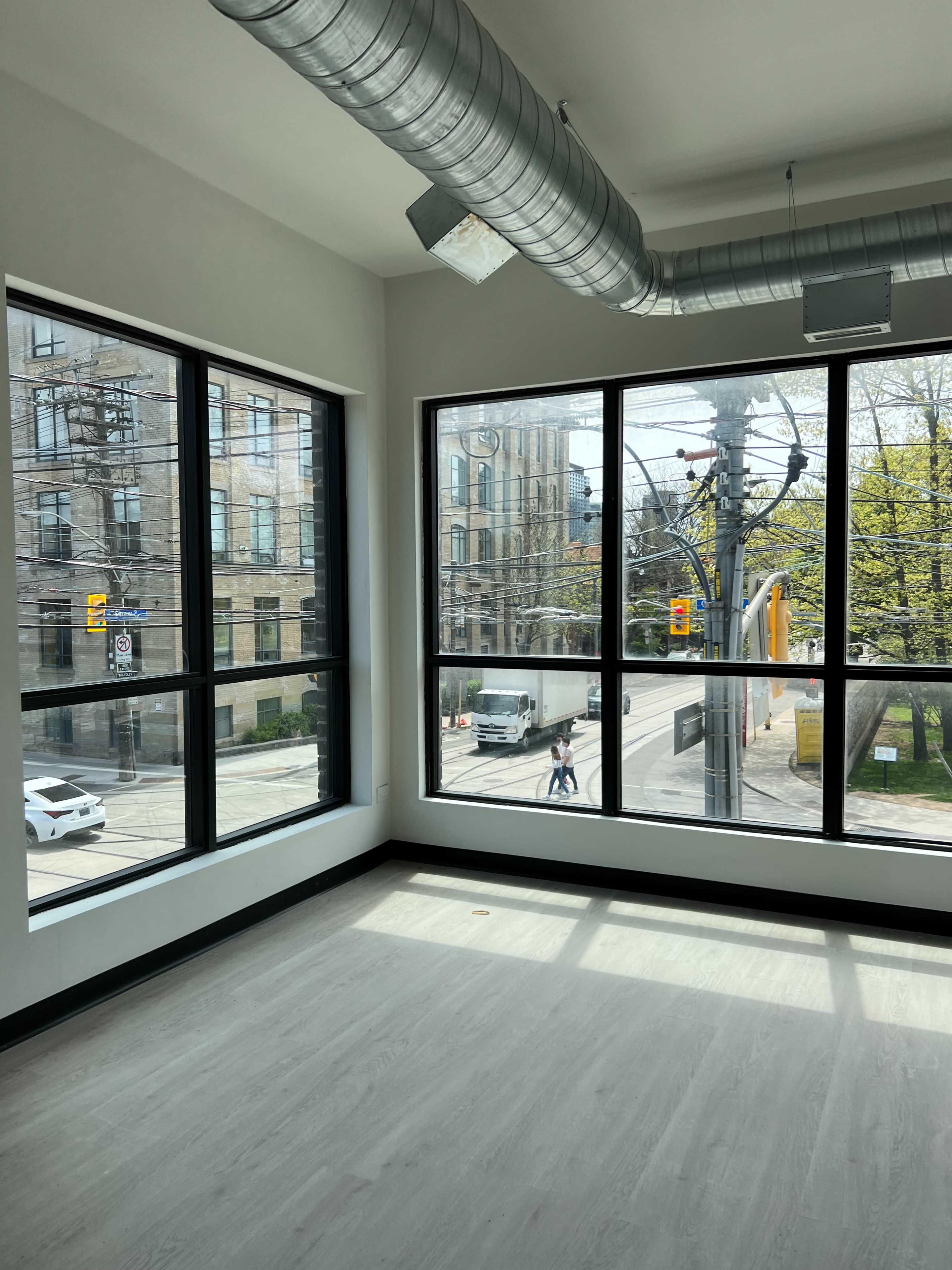 A spacious room with large windows overlooking a street with vehicles and pedestrians outside.