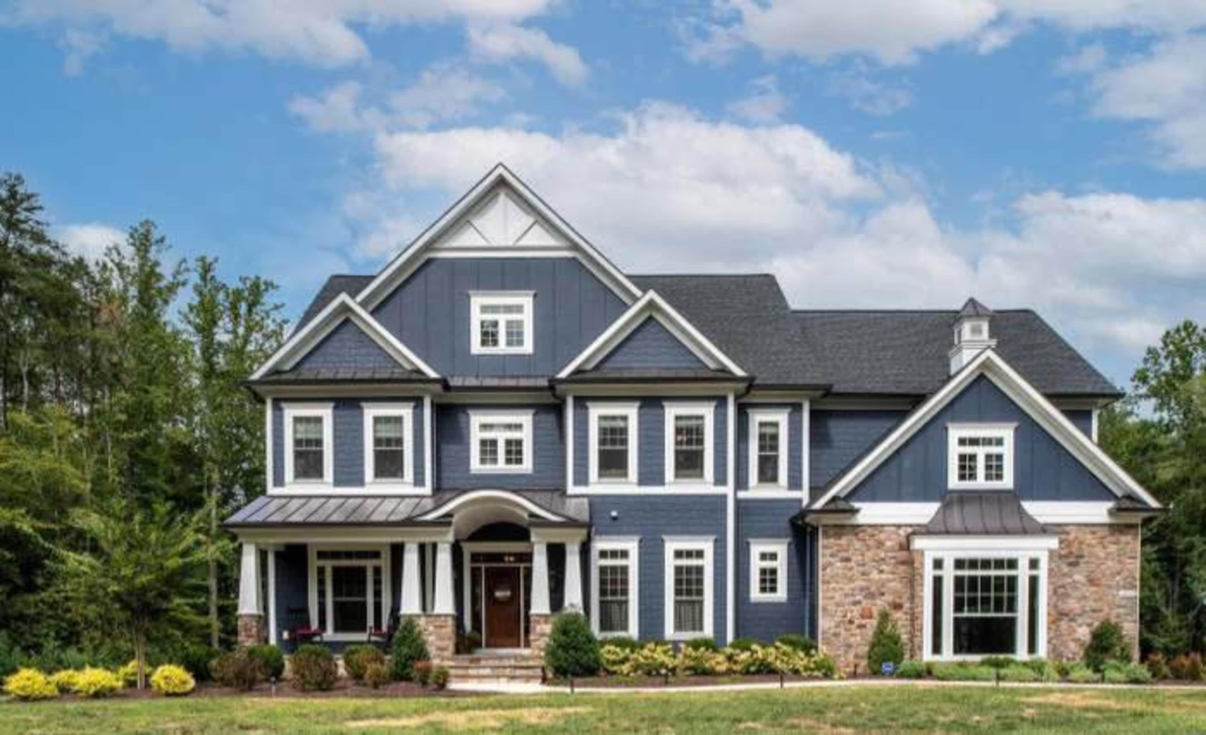 A large blue and stone house with multiple gables and a landscaped front yard.