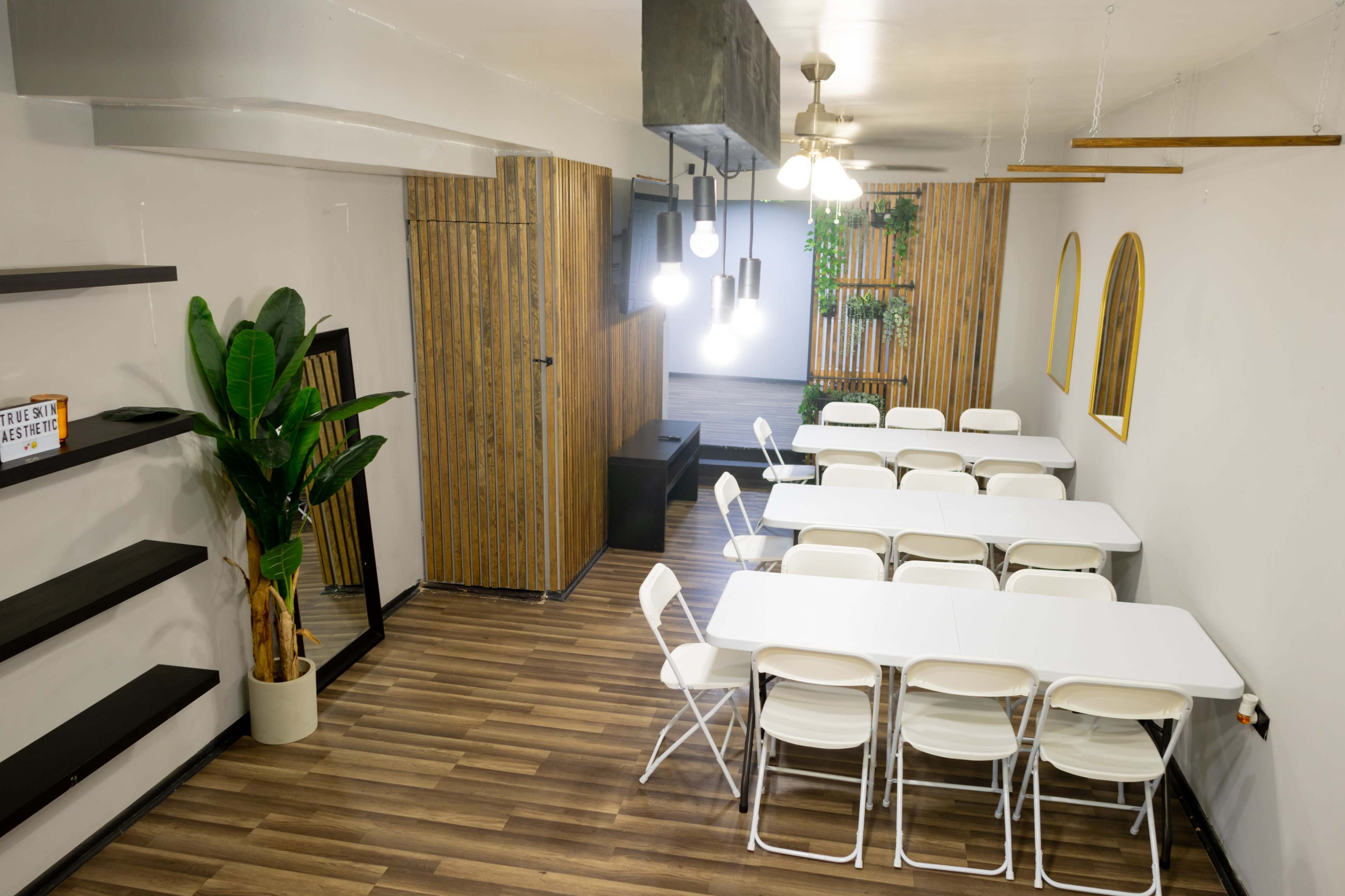 The image shows a modern meeting room with white folding tables arranged in a U-shape and wooden panel accents on the walls.