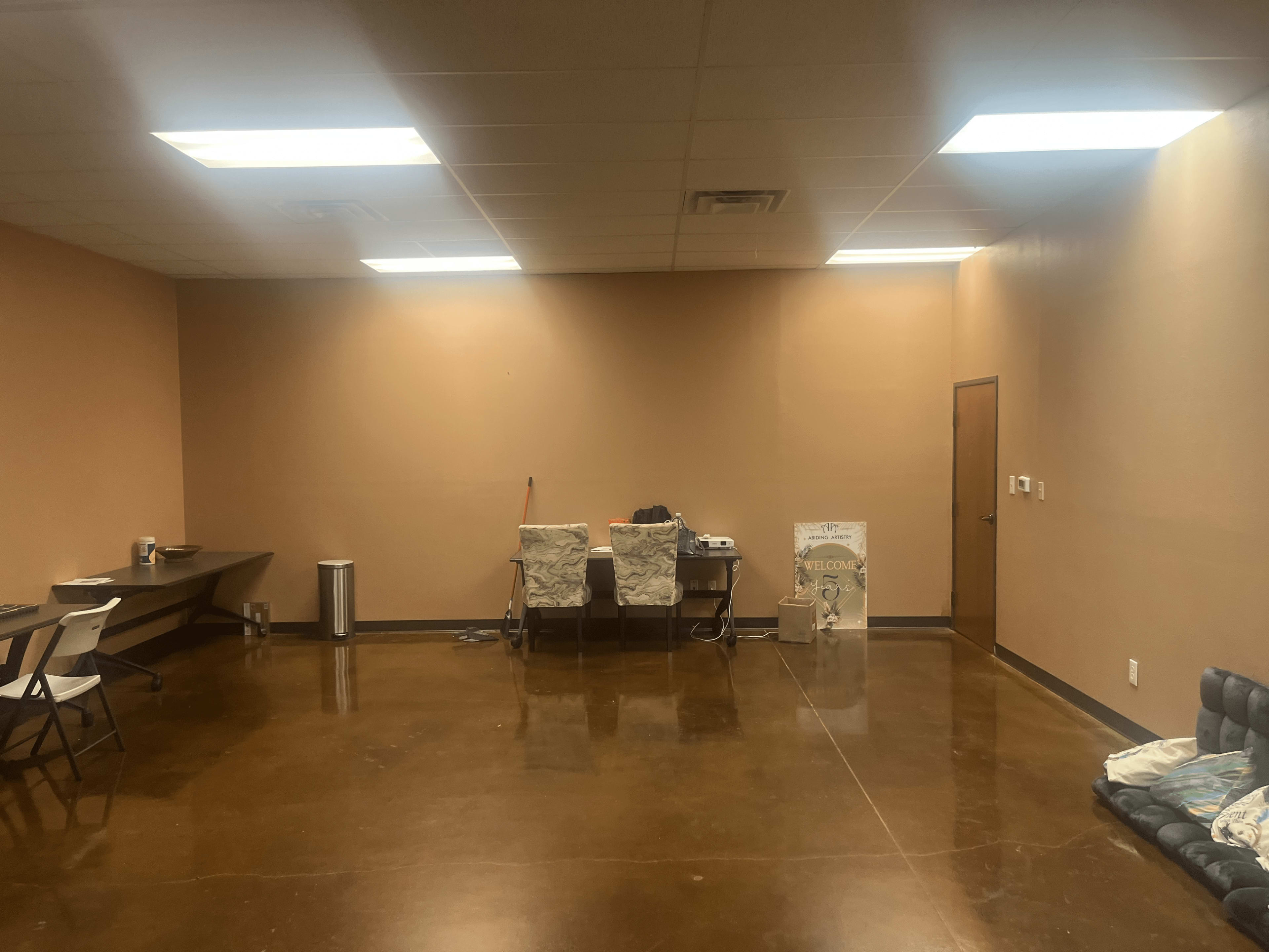 A sparsely furnished room with a table and chairs on one side and a couch on the other.