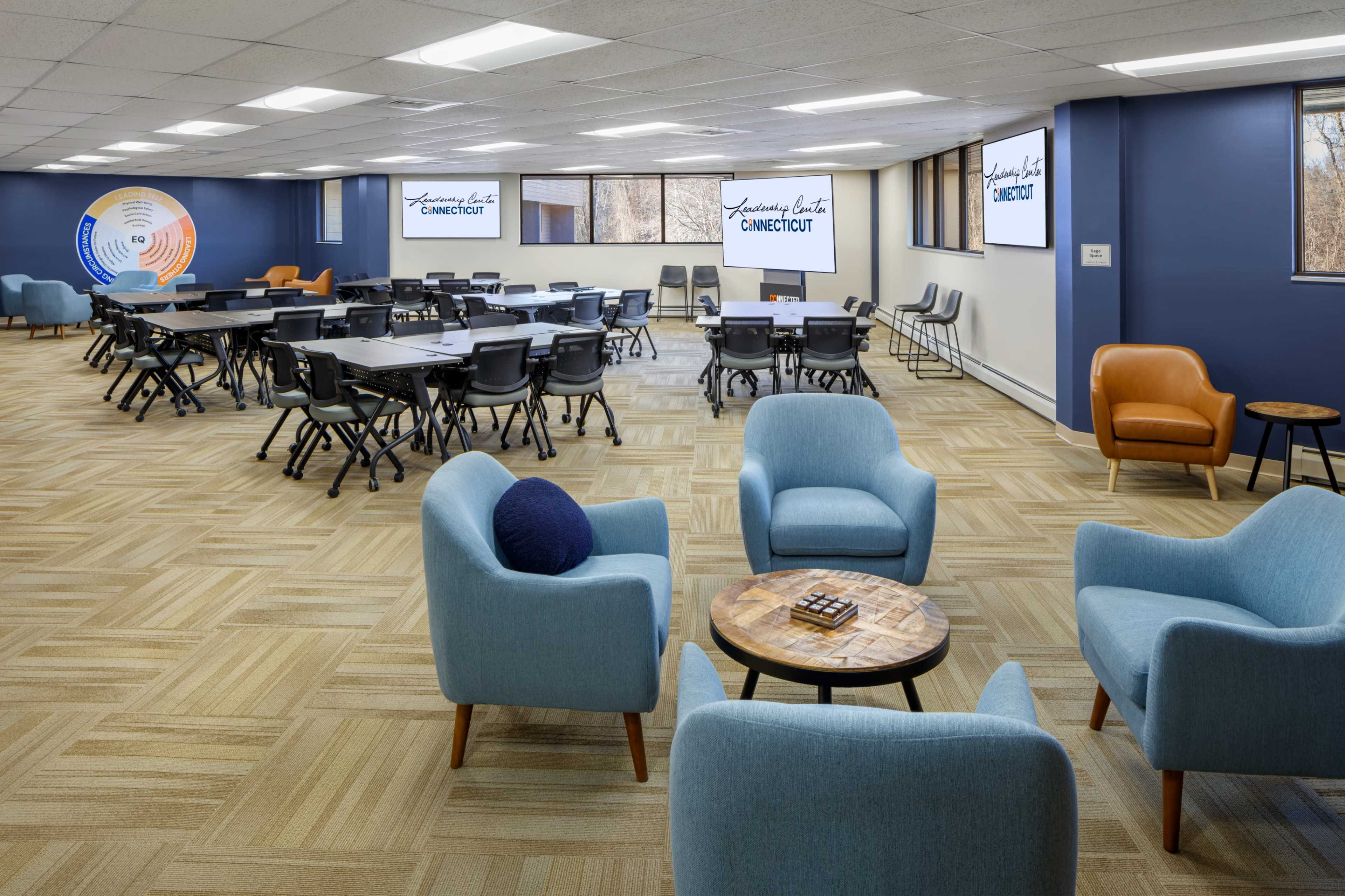 The image shows a spacious, modern meeting room with multiple tables and chairs arranged for collaboration, featuring large screens displaying the text "Connecticut."