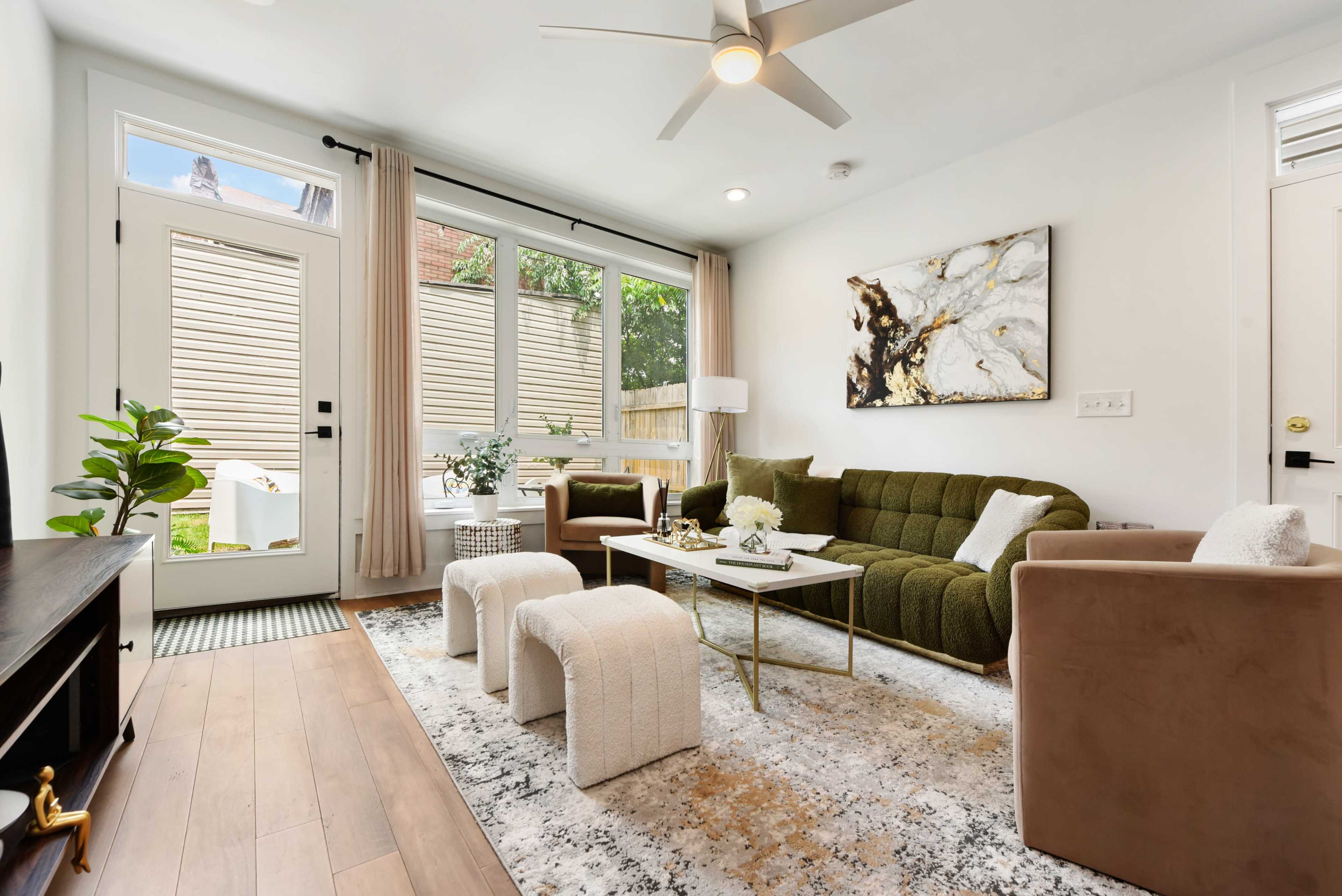The image shows a modern living room with a green sofa, two beige chairs, a coffee table, and a decorative rug under soft lighting.