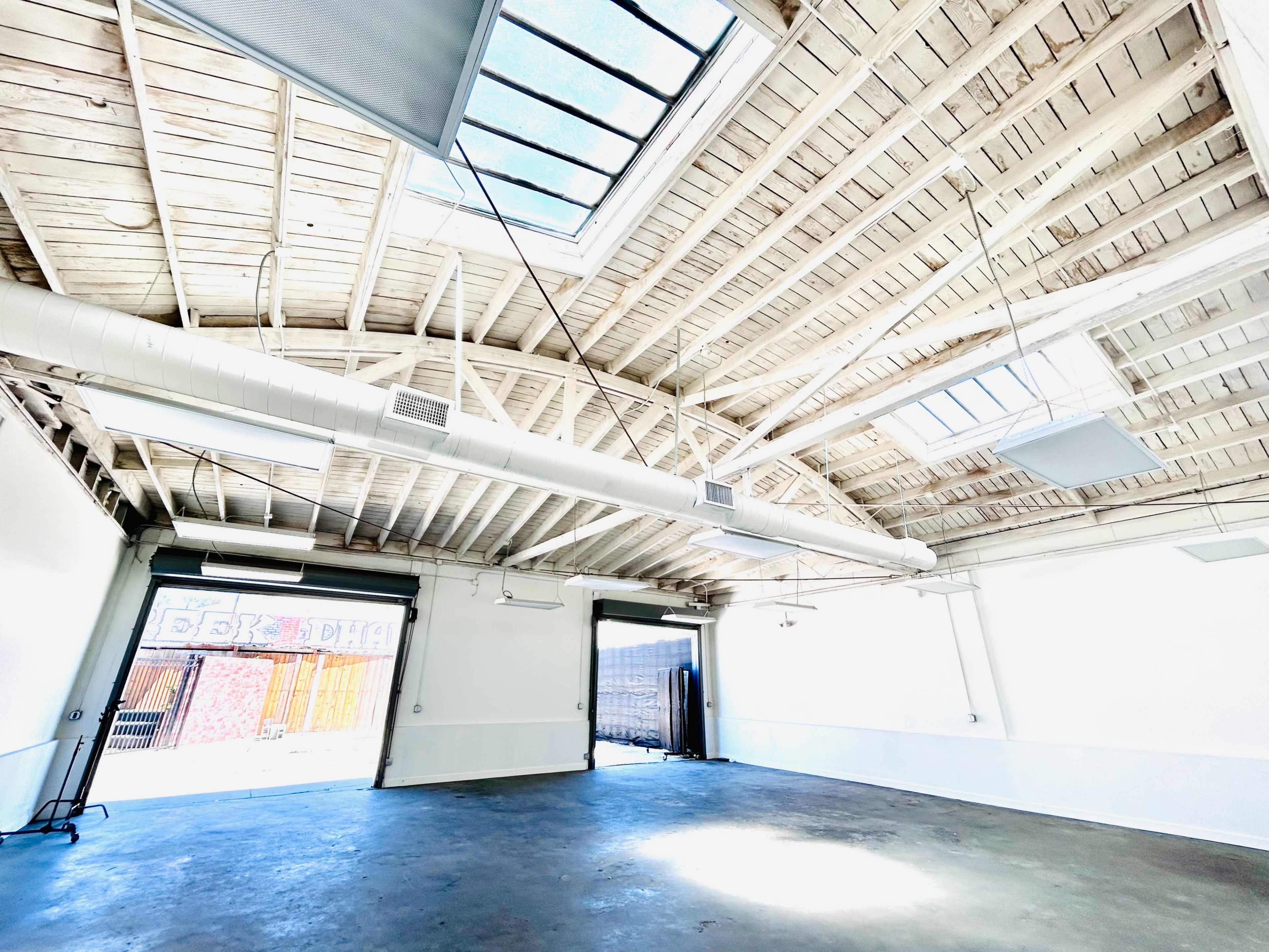 The image shows a bright, open interior space with a wooden ceiling and large skylights.