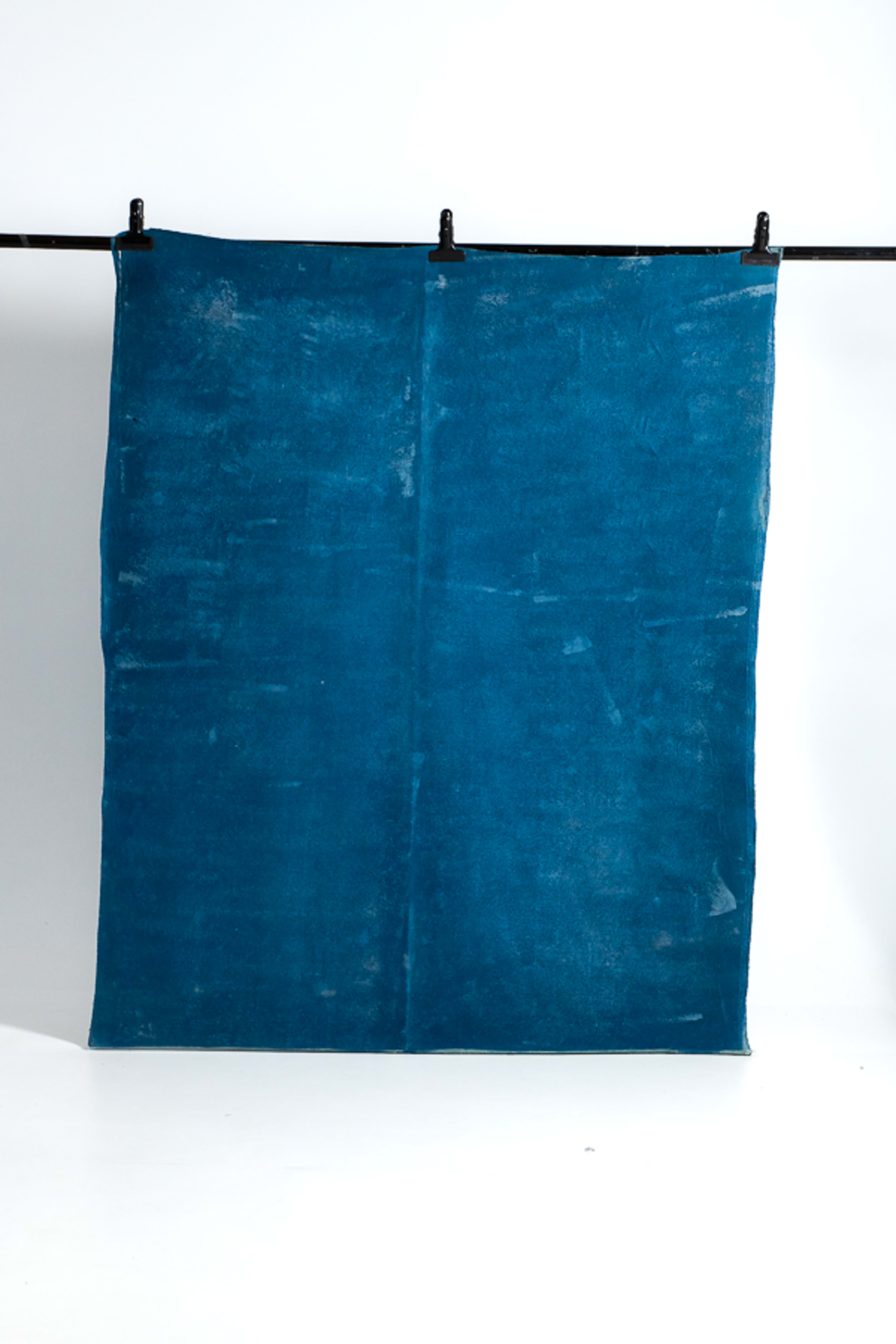 A large blue fabric is hanging from a rod with clips against a white background.