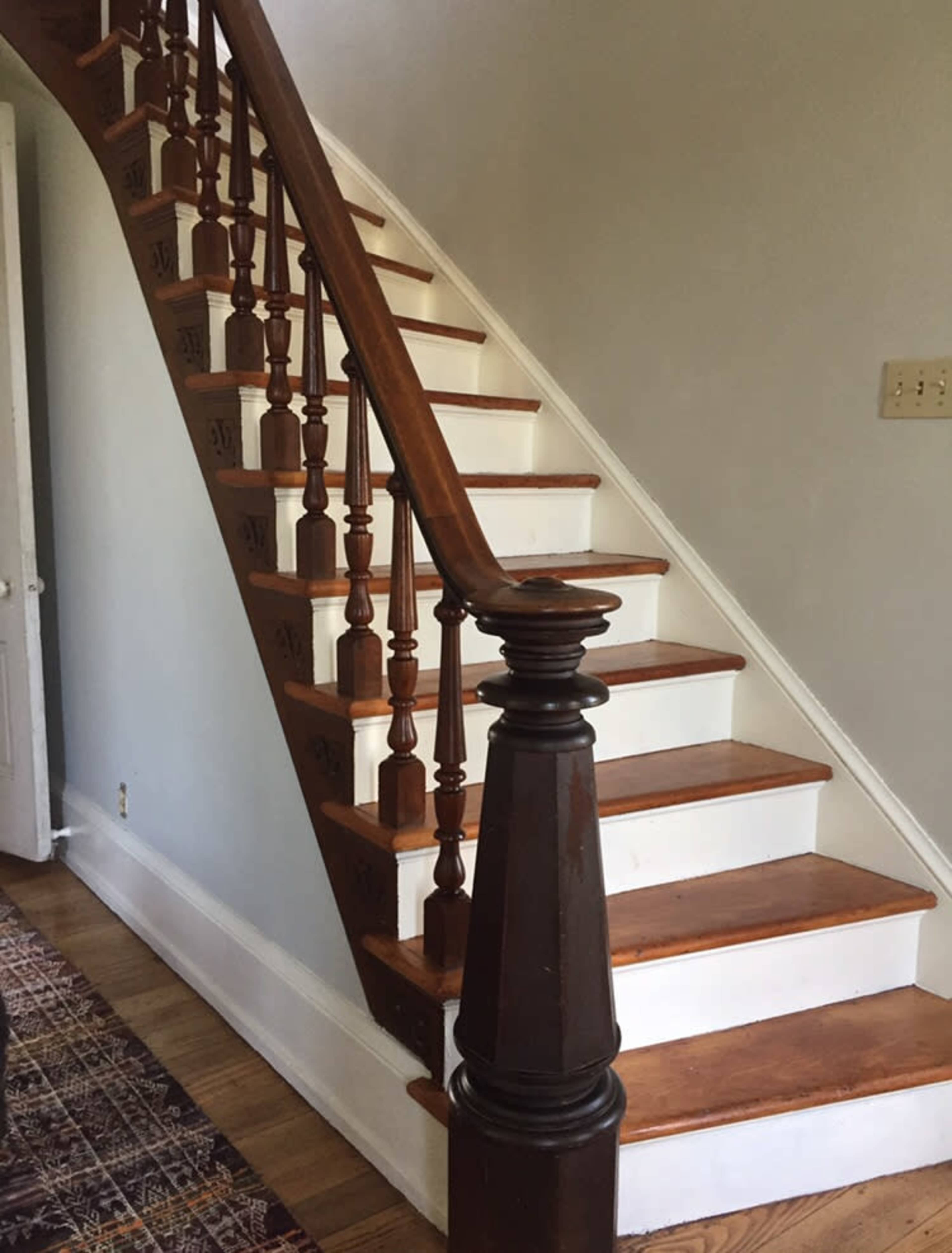 A wooden staircase with polished handrails and white risers, leading to an upper level in a home.