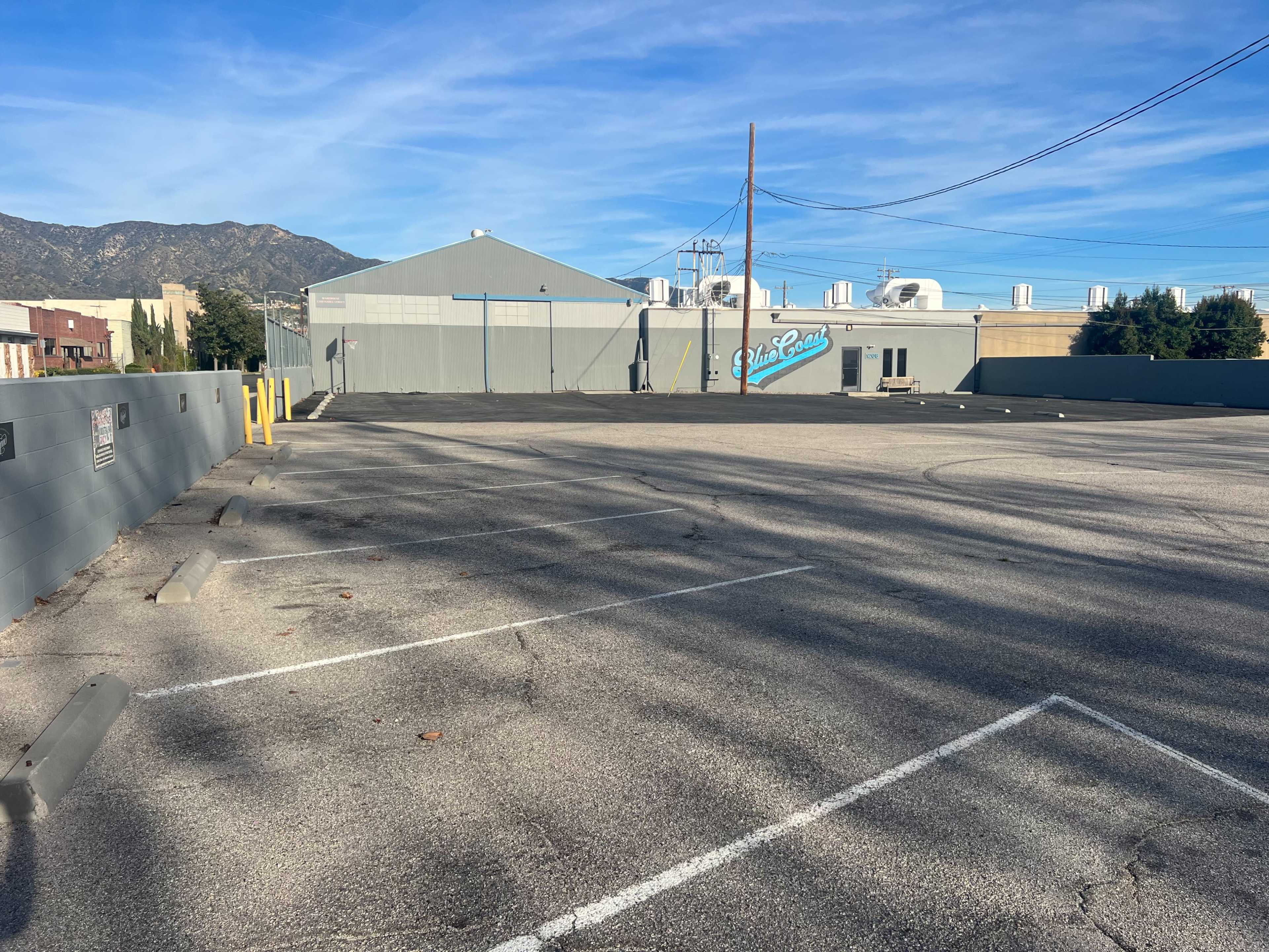 An empty parking lot with several vacant spaces and a building in the background.