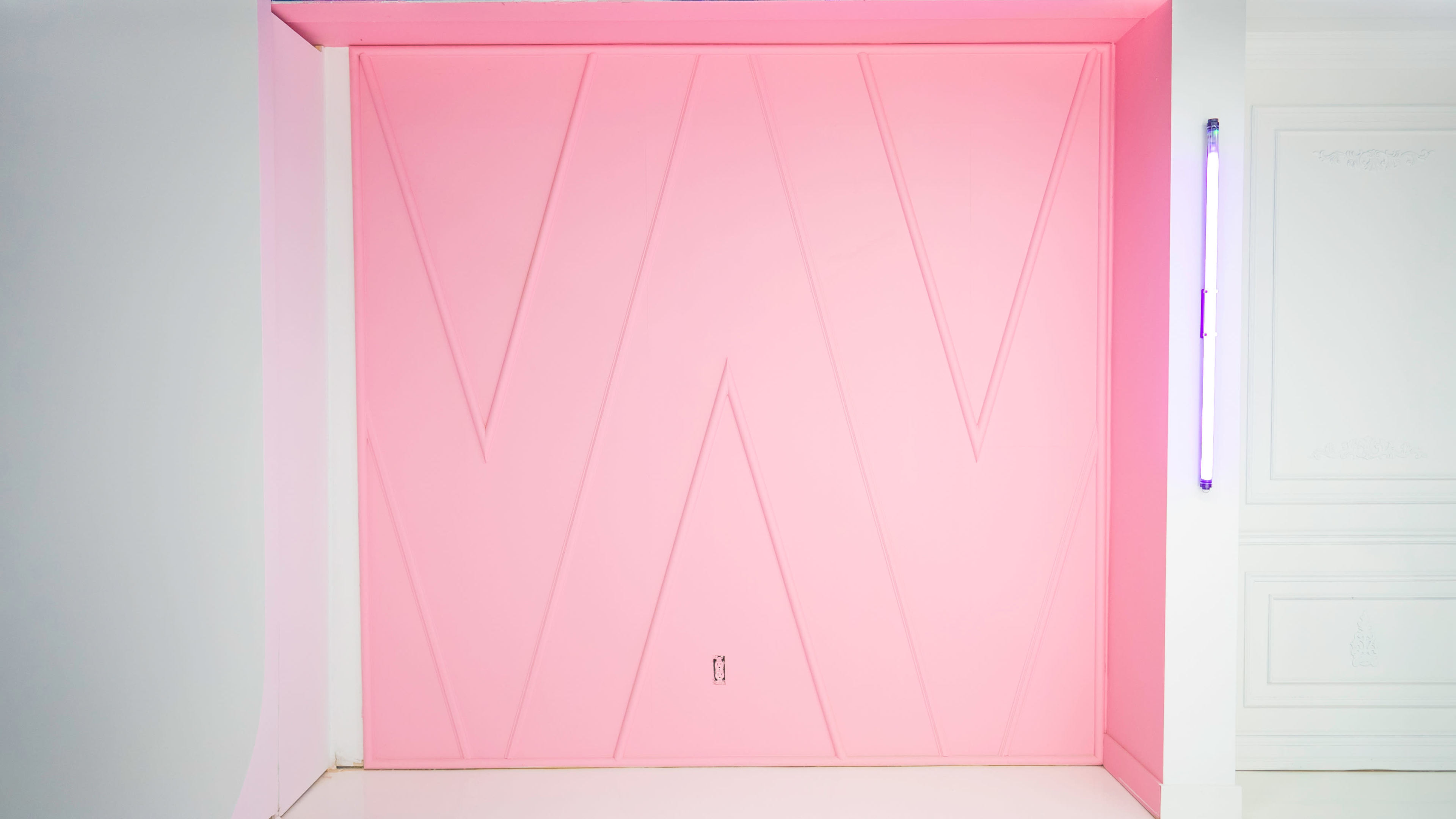 A large, textured pink wall with a prominent "W" design.