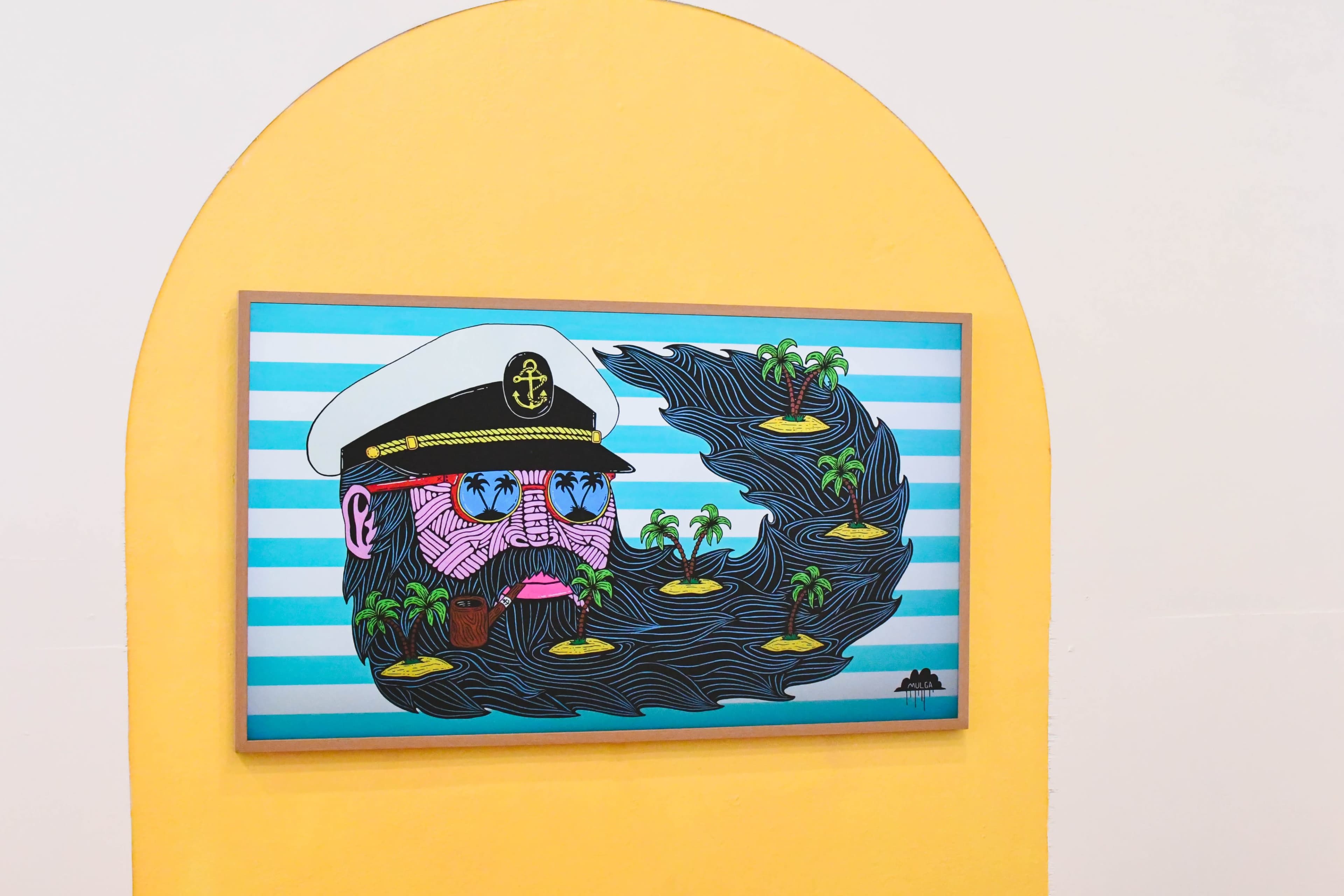A colorful mural depicts a bearded man in a captain's hat surrounded by palm trees and waves.