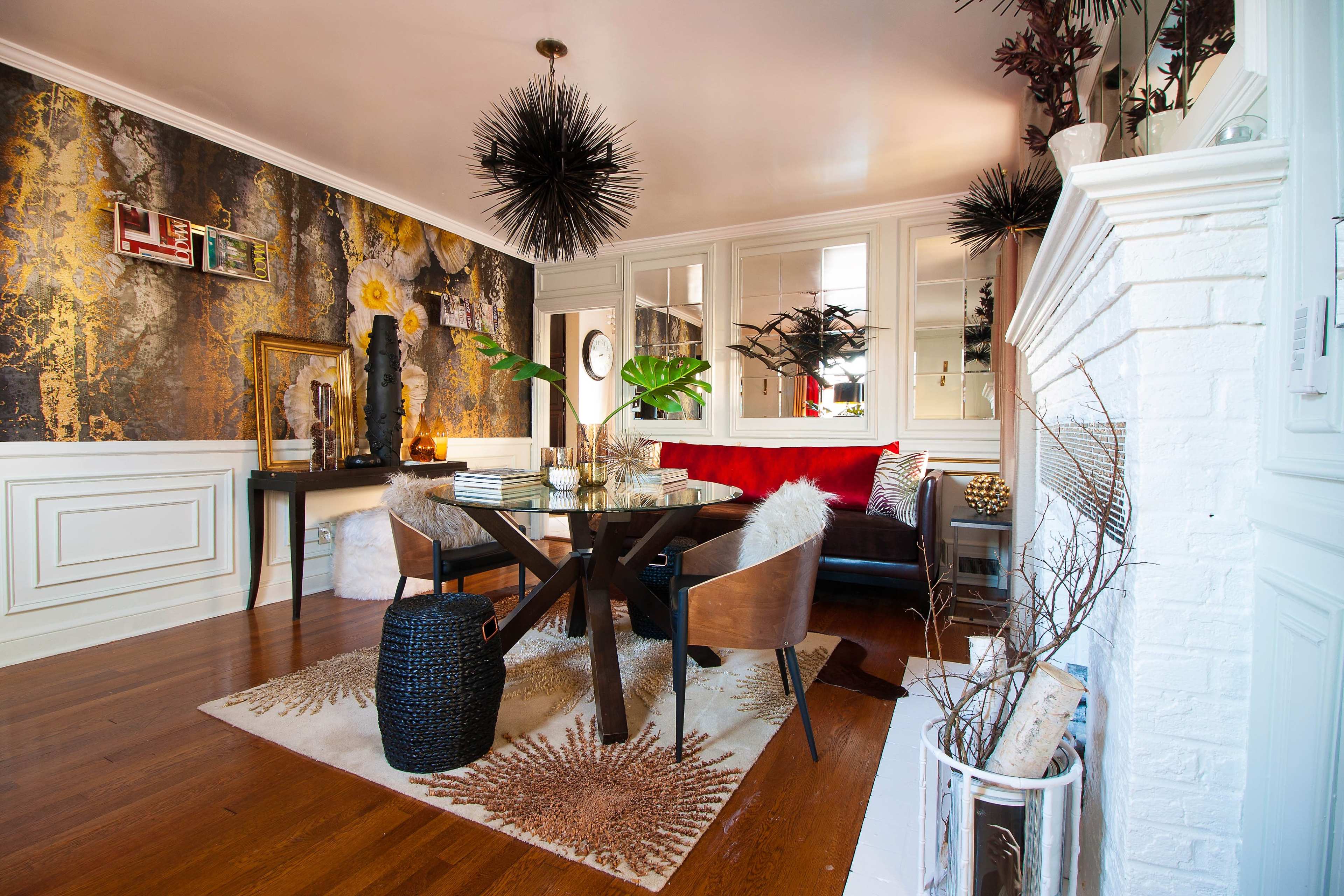 A stylish dining area with a round table, modern chairs, and decorative elements like a textured wall, a large mirror, and a fireplace.