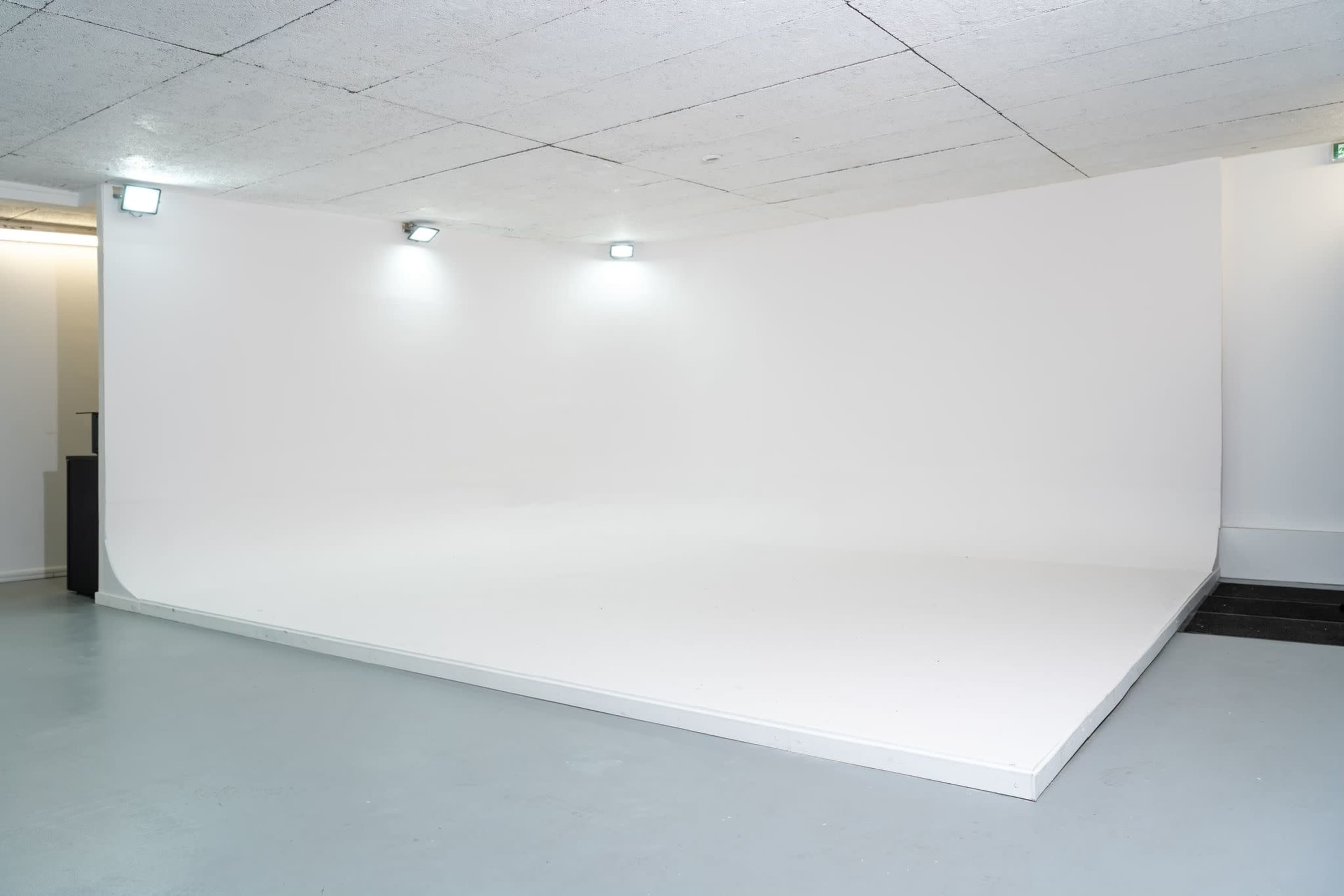 A minimalist white studio space with a smooth floor and curved backdrop.