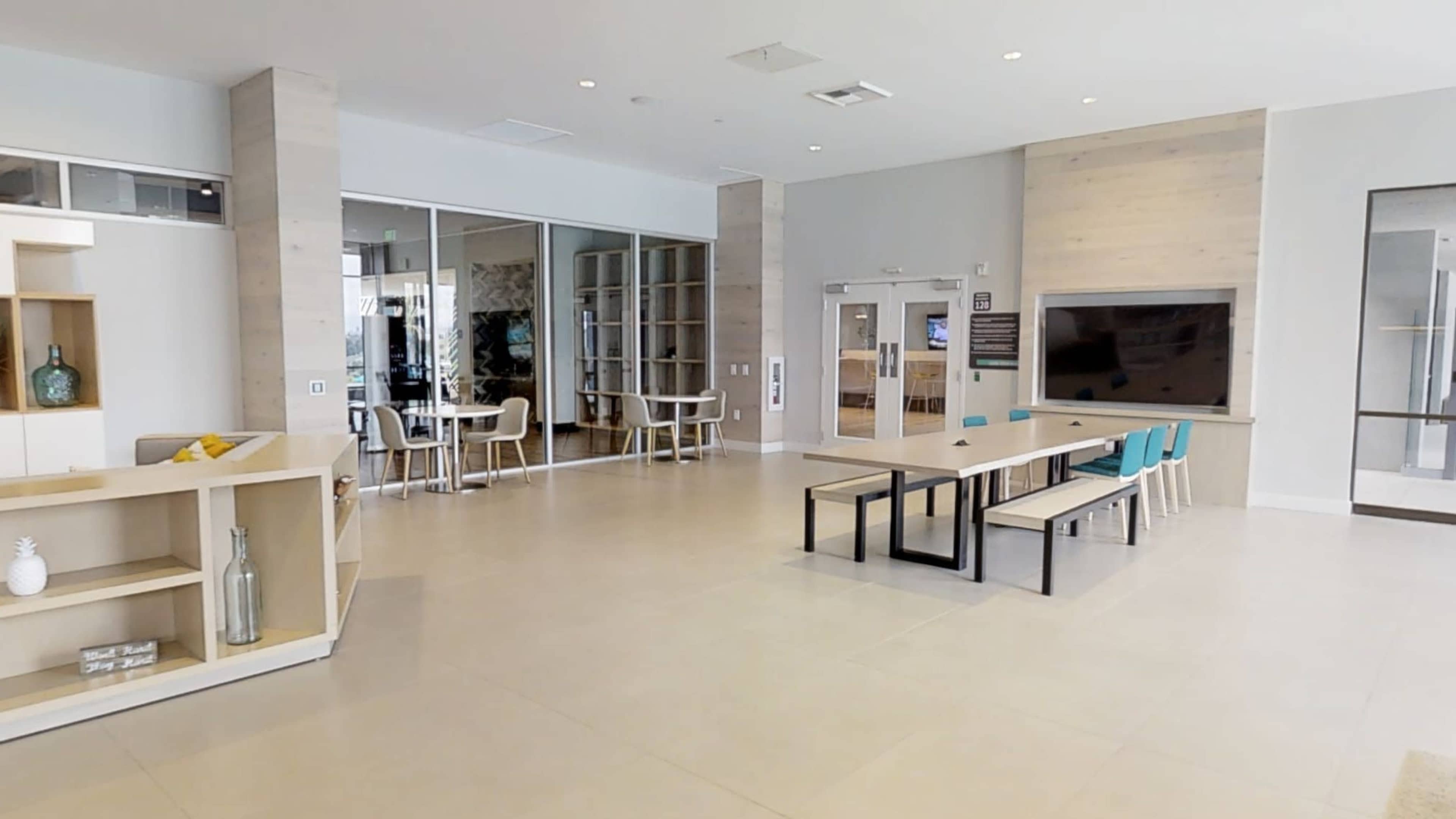 A modern, open lobby area with seating arrangements, a television, and a decorative wall.