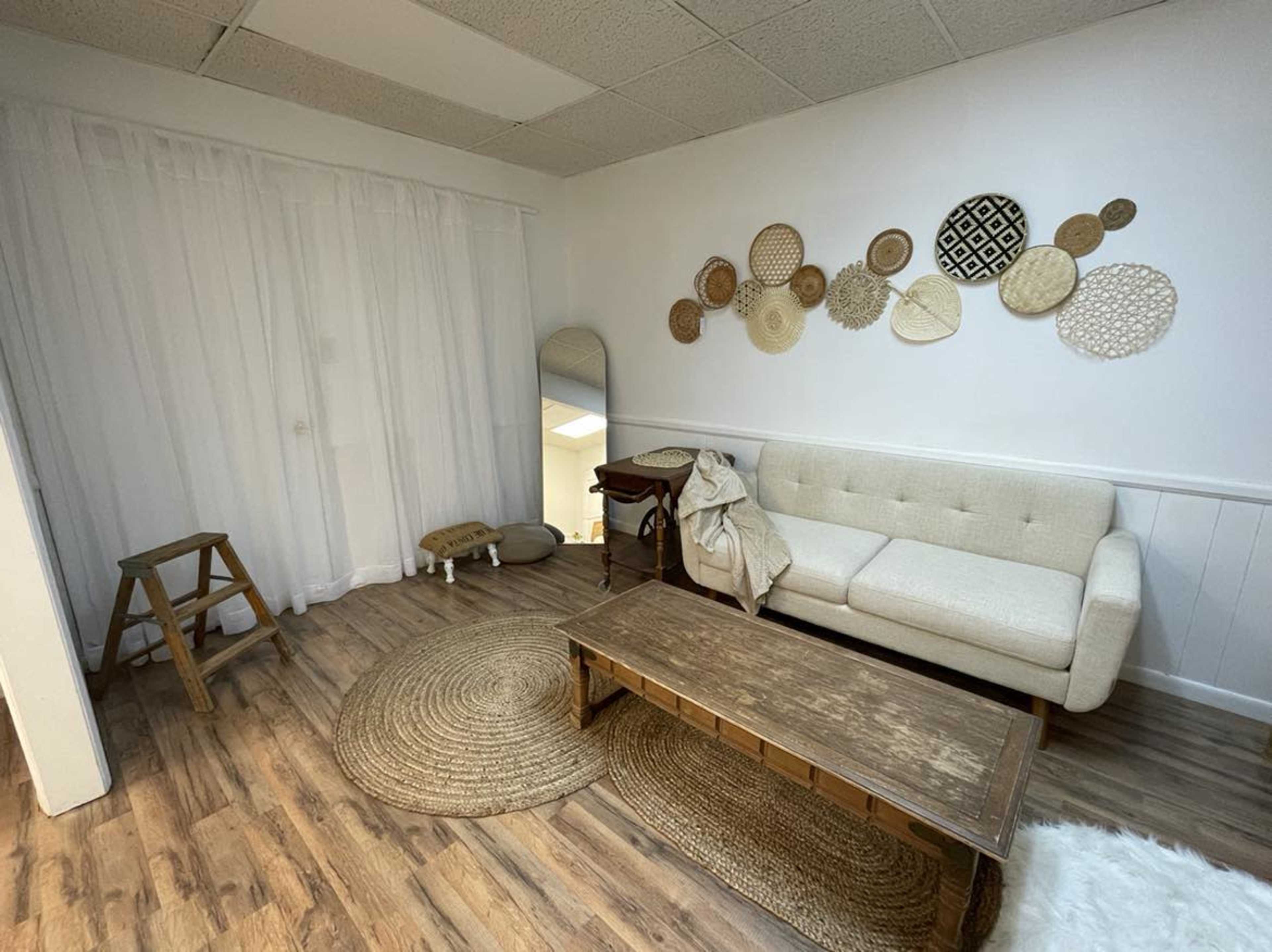 A minimalist living room with a light-colored couch, a wooden coffee table, and decorative woven wall hangings.