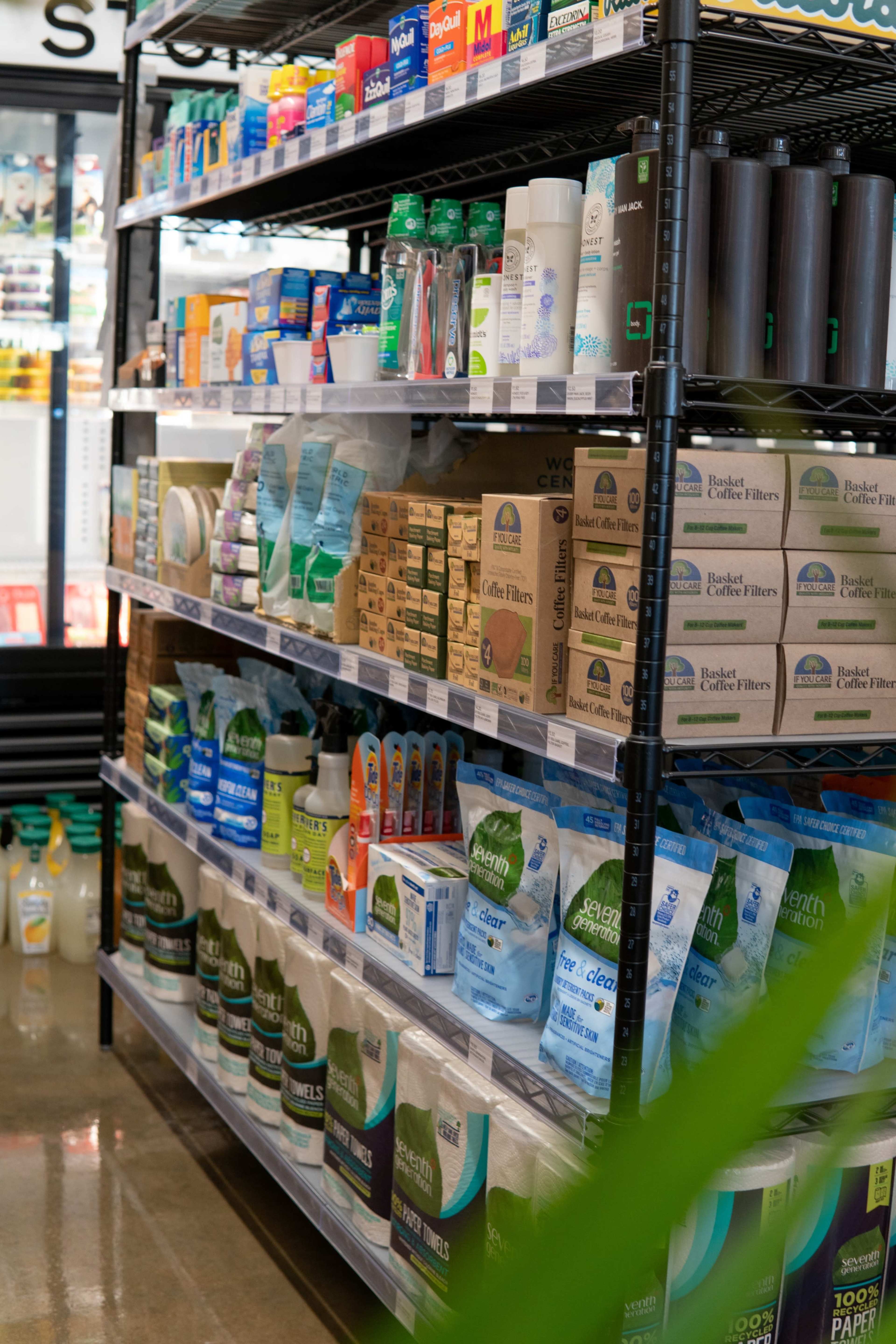 A retail shelf displays a variety of household products, including cleaning supplies, personal care items, and paper goods.