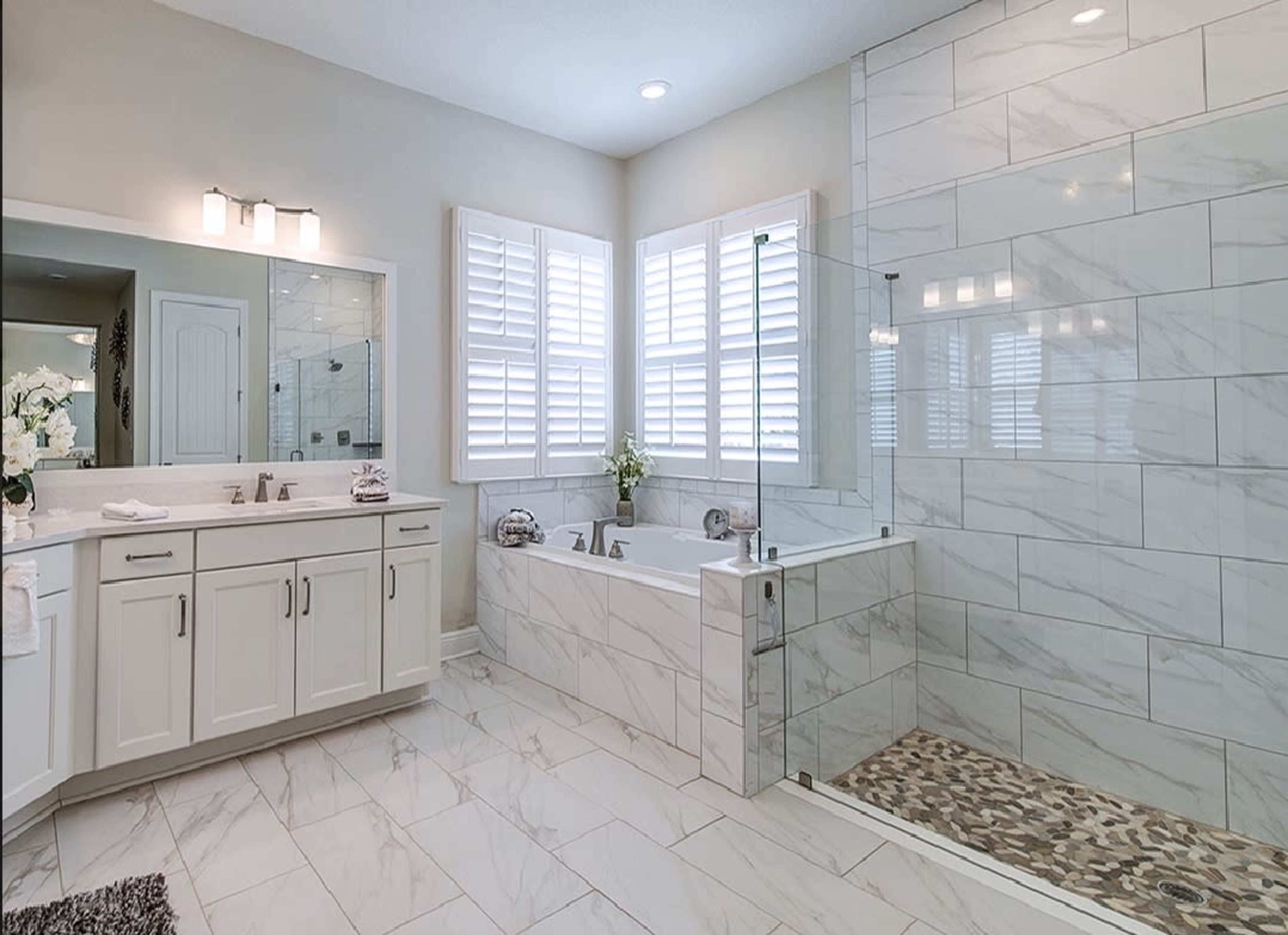 A modern bathroom featuring a freestanding tub, a glass shower enclosure, and double sinks with a large mirror.
