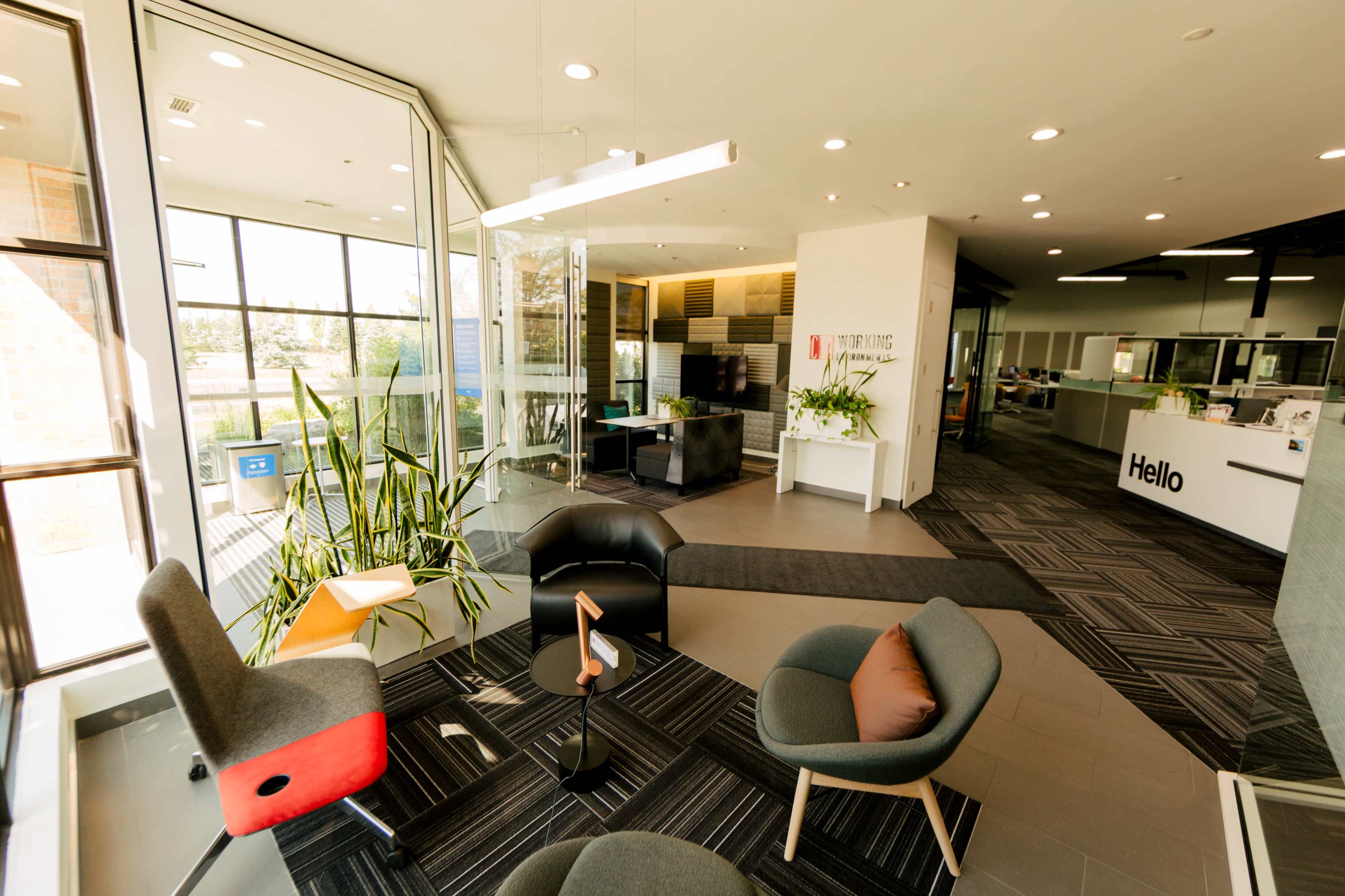The image shows a modern office lobby featuring stylish seating, large windows, and a reception area with a sign that says "Hello."