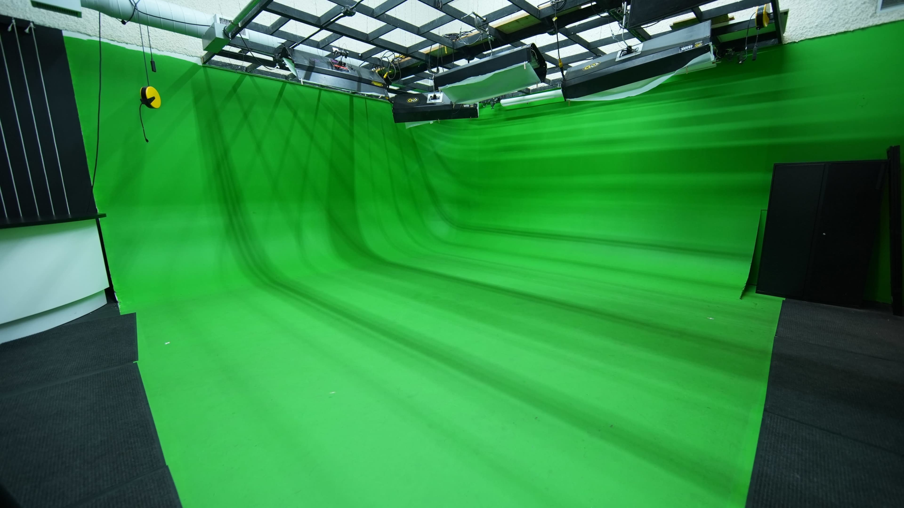 The image shows a spacious green screen studio with smooth, green flooring and walls, designed for film and video production.