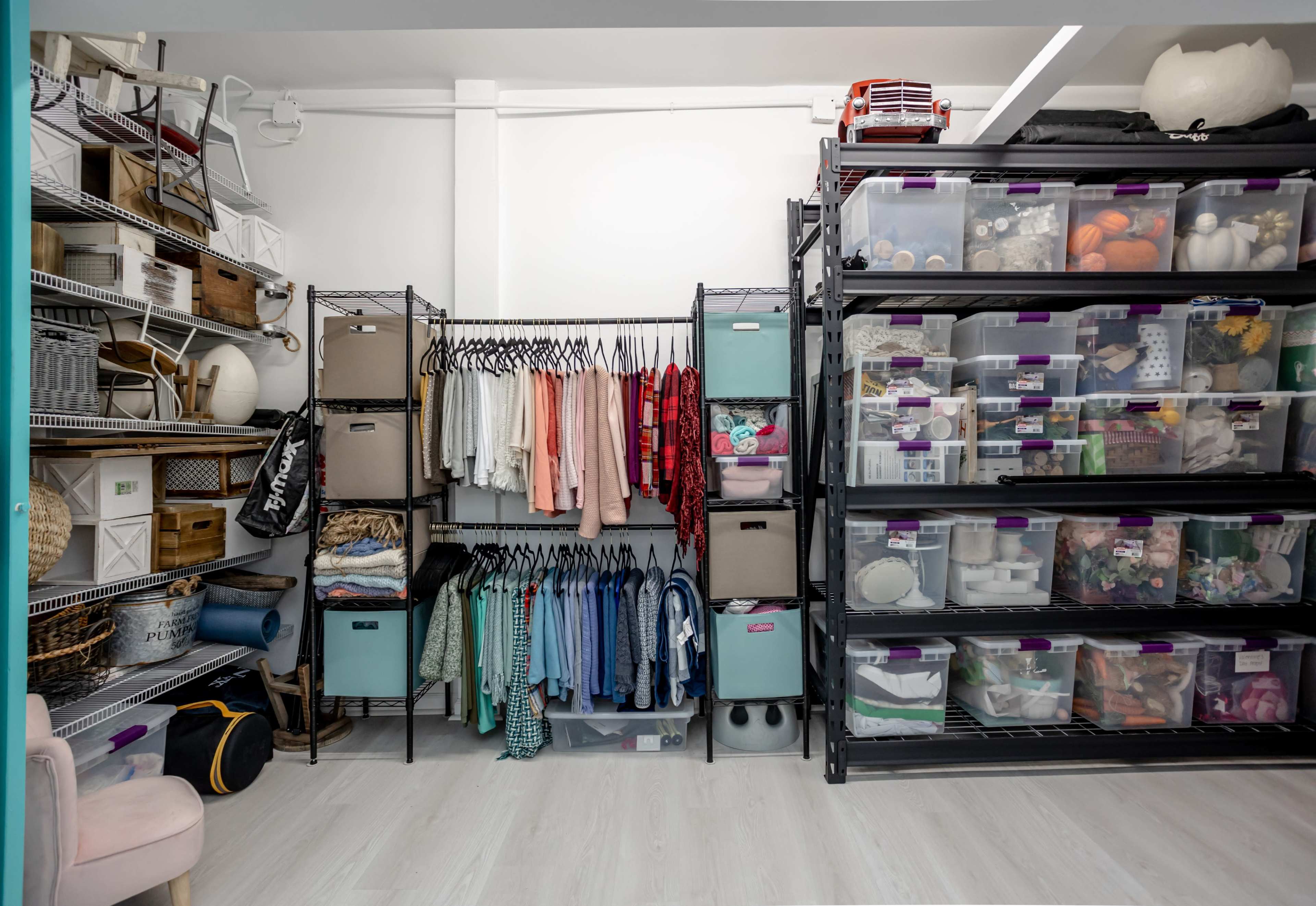 A well-organized storage room with shelves holding clear bins and neatly arranged clothing items.