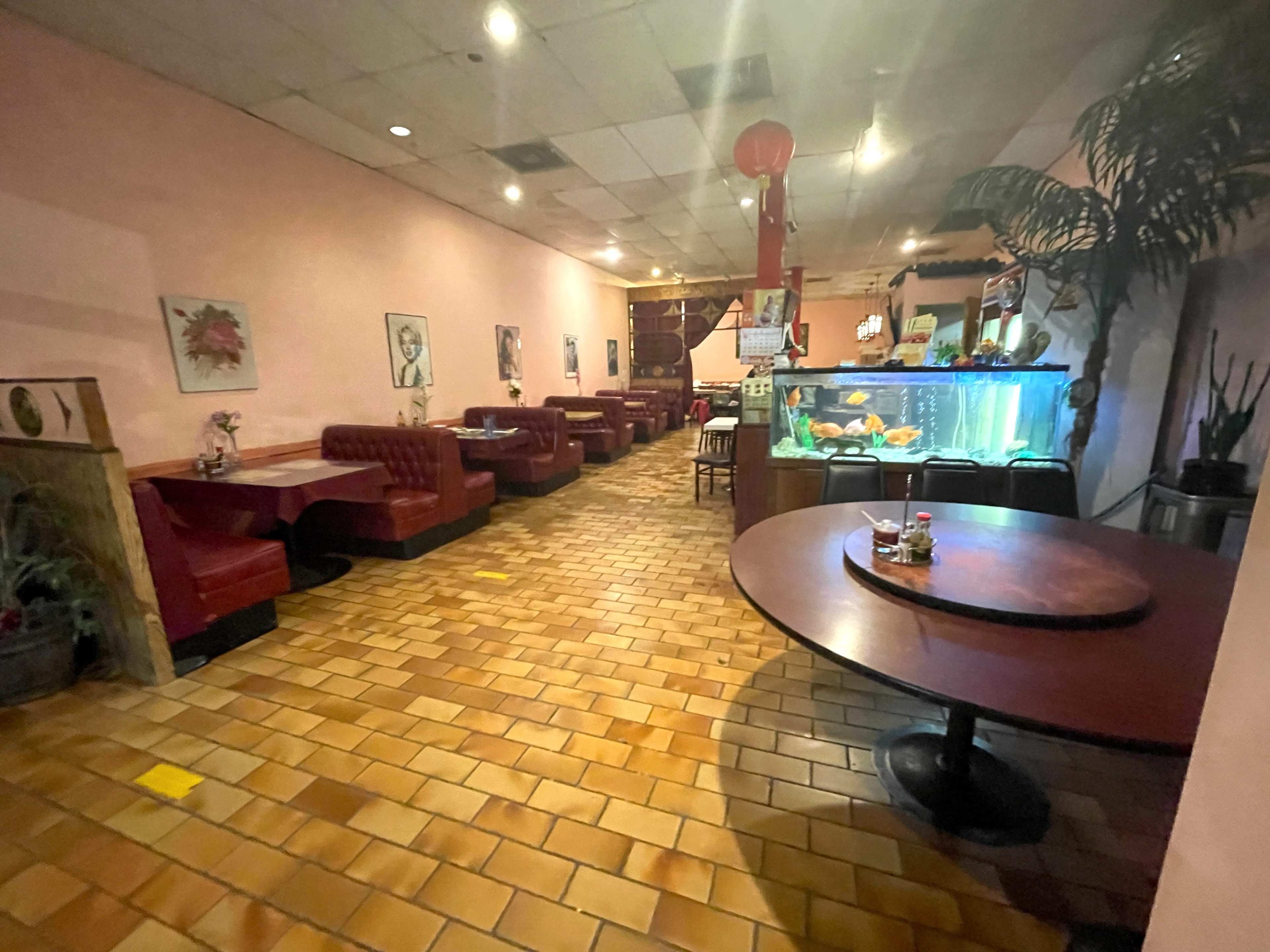 The interior of a restaurant features pink walls, red booths, a tiled floor, and an aquarium at one end.