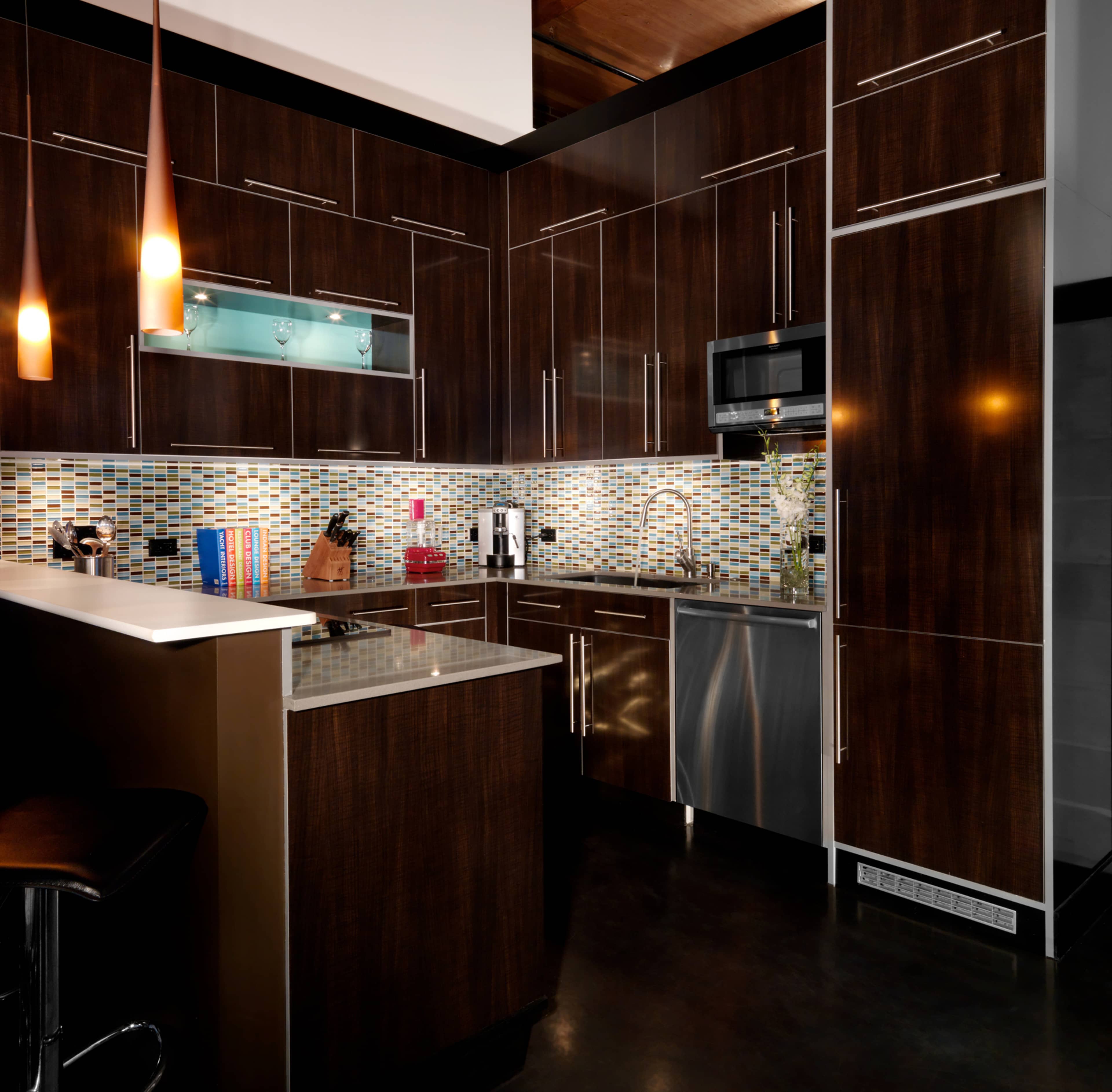 The kitchen features dark wooden cabinetry, a mosaic tile backsplash, and modern stainless steel appliances.
