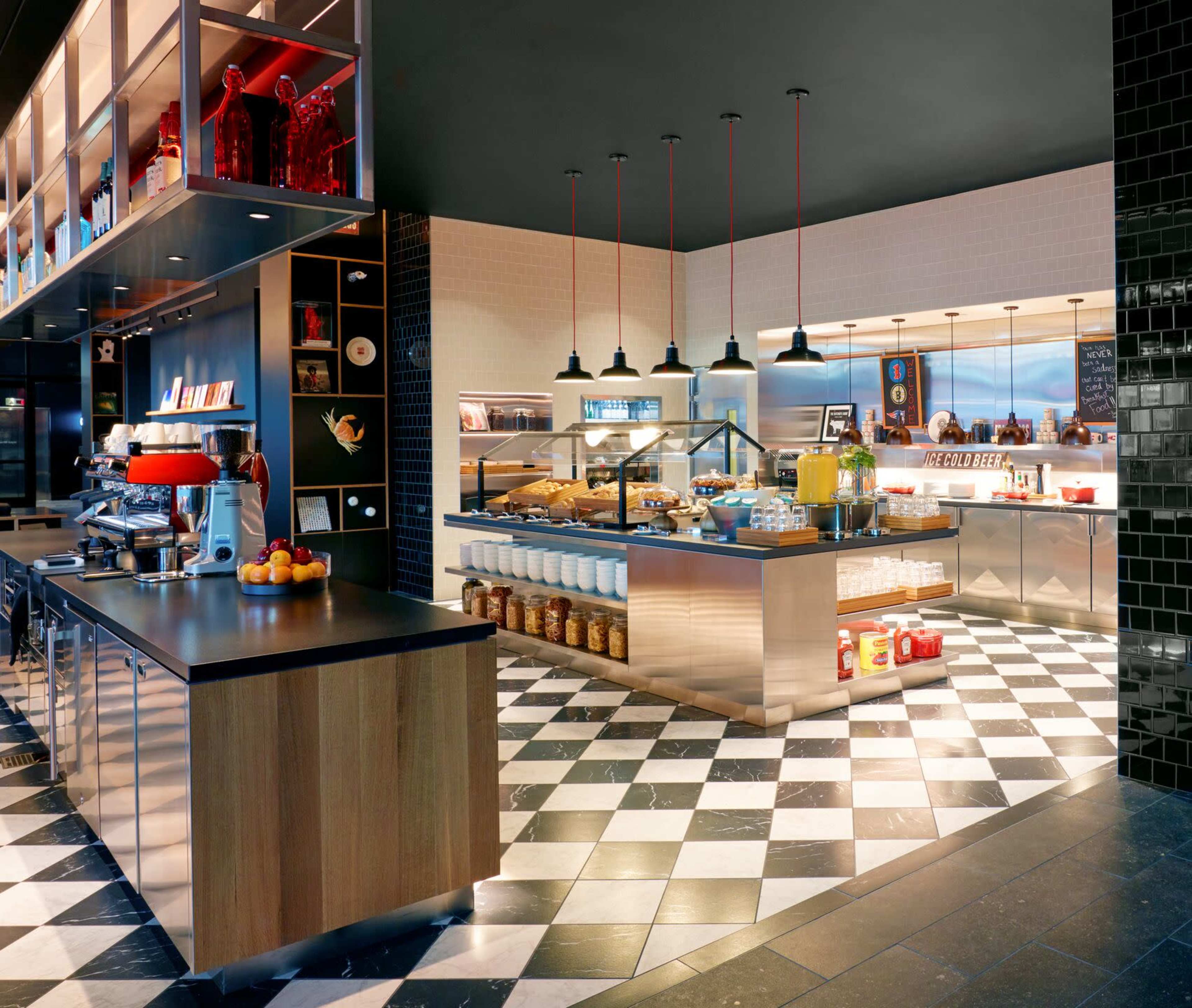 A modern café interior with a checkerboard floor, a sleek serving counter, and various food and beverage displays.