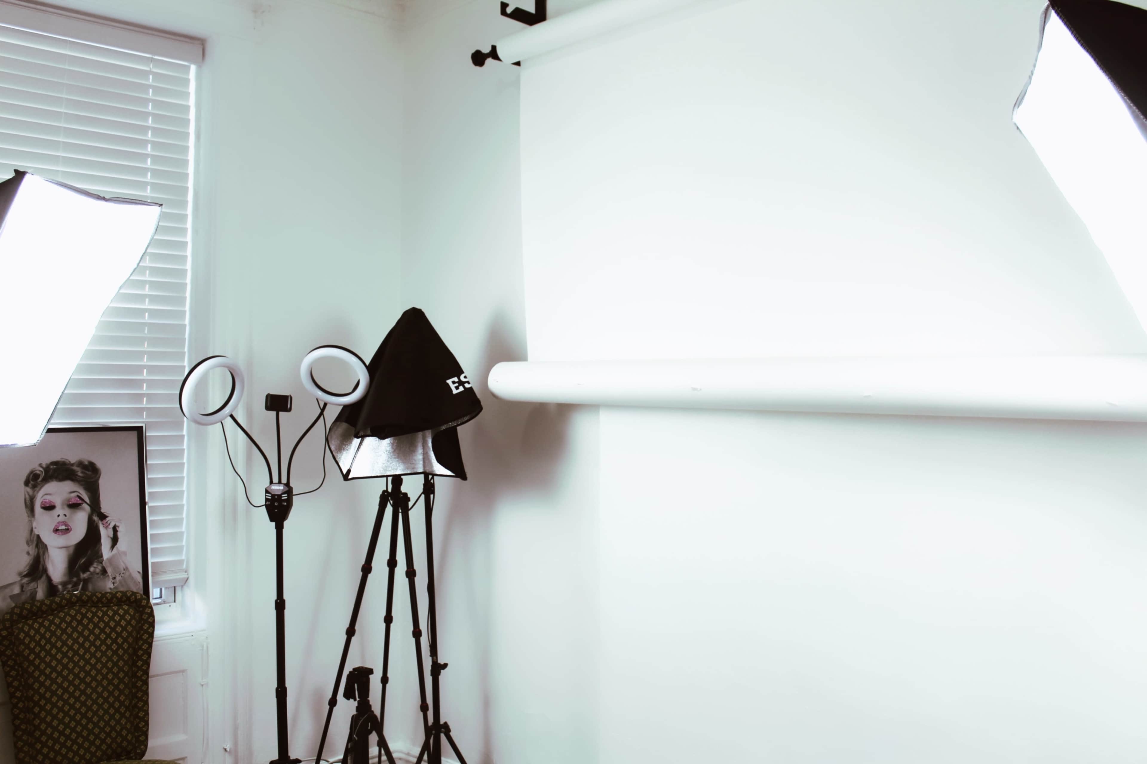 A photography studio setup with a white backdrop, lighting equipment, and a decorative chair in the corner.