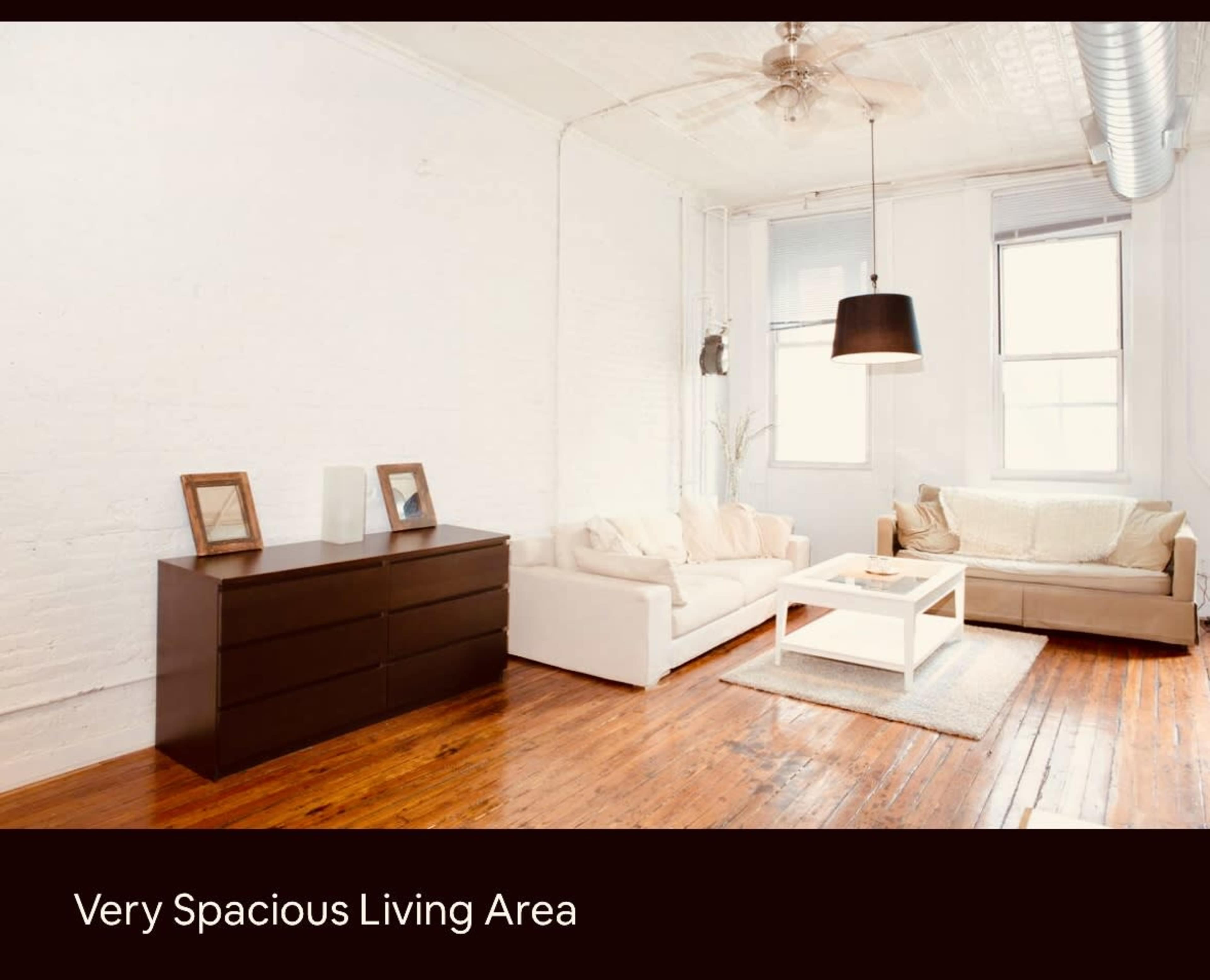 The image features a bright living area with a light-colored couch, a darker sofa, a coffee table, and wooden flooring.