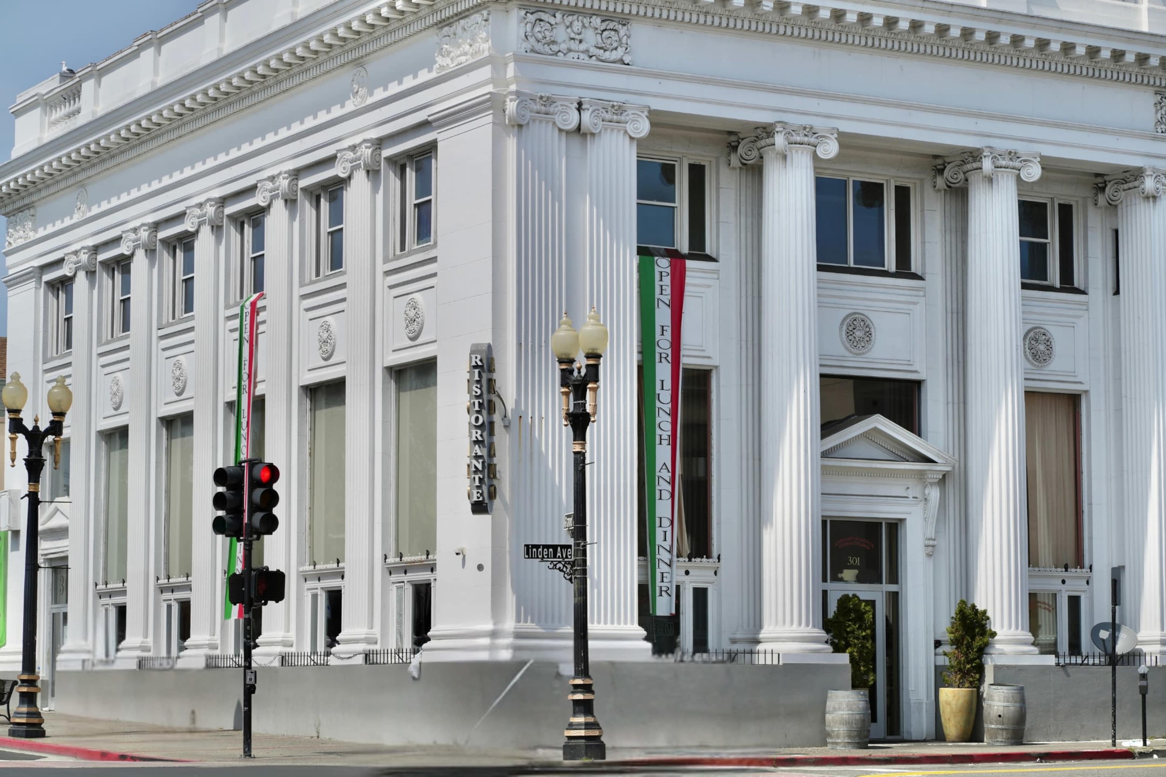 A historic white building with tall columns features restaurant signage and decorative banners.