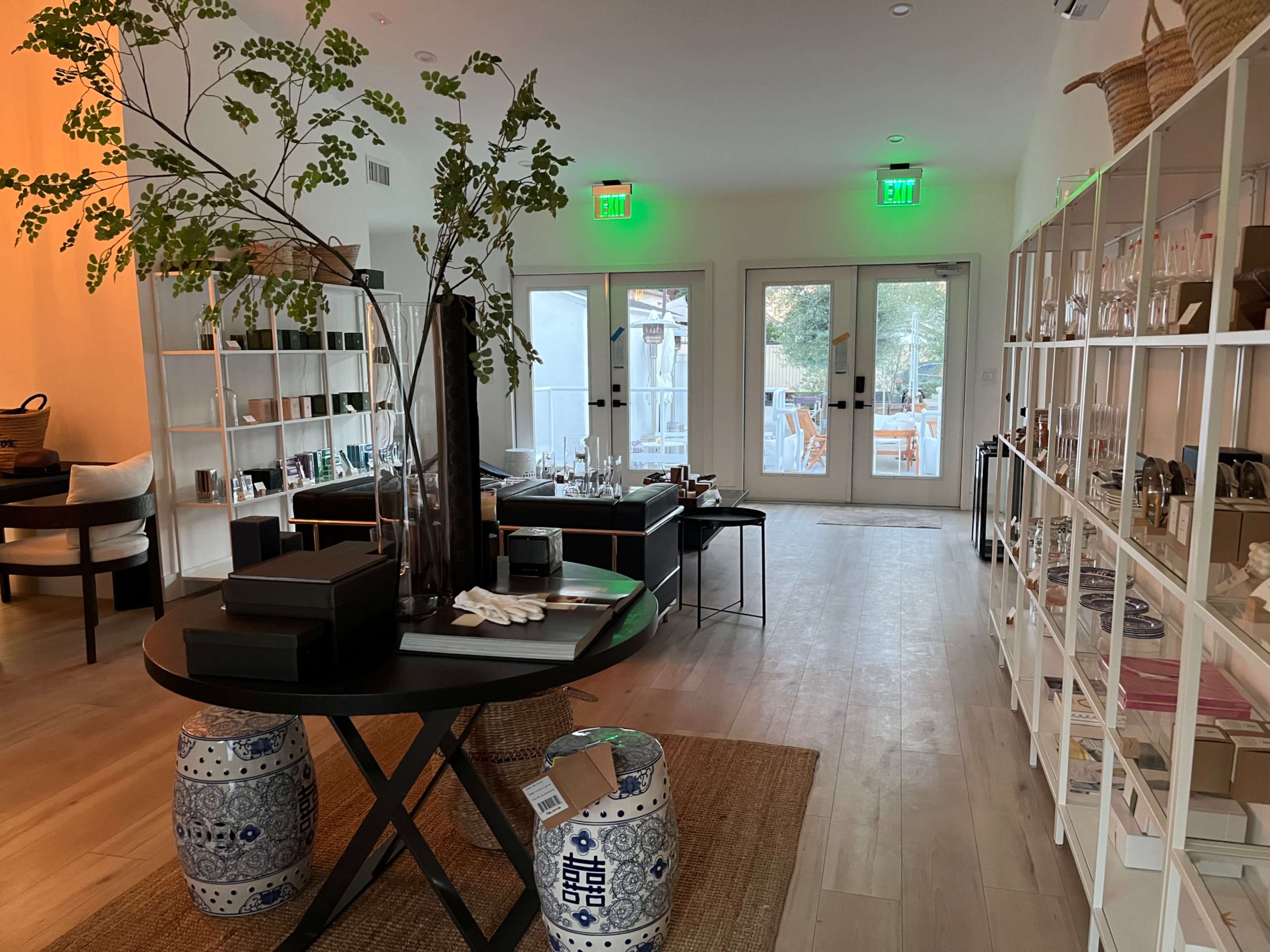 A modern retail space with minimalist decor, featuring a round table with a plant in the center and shelves displaying various products.