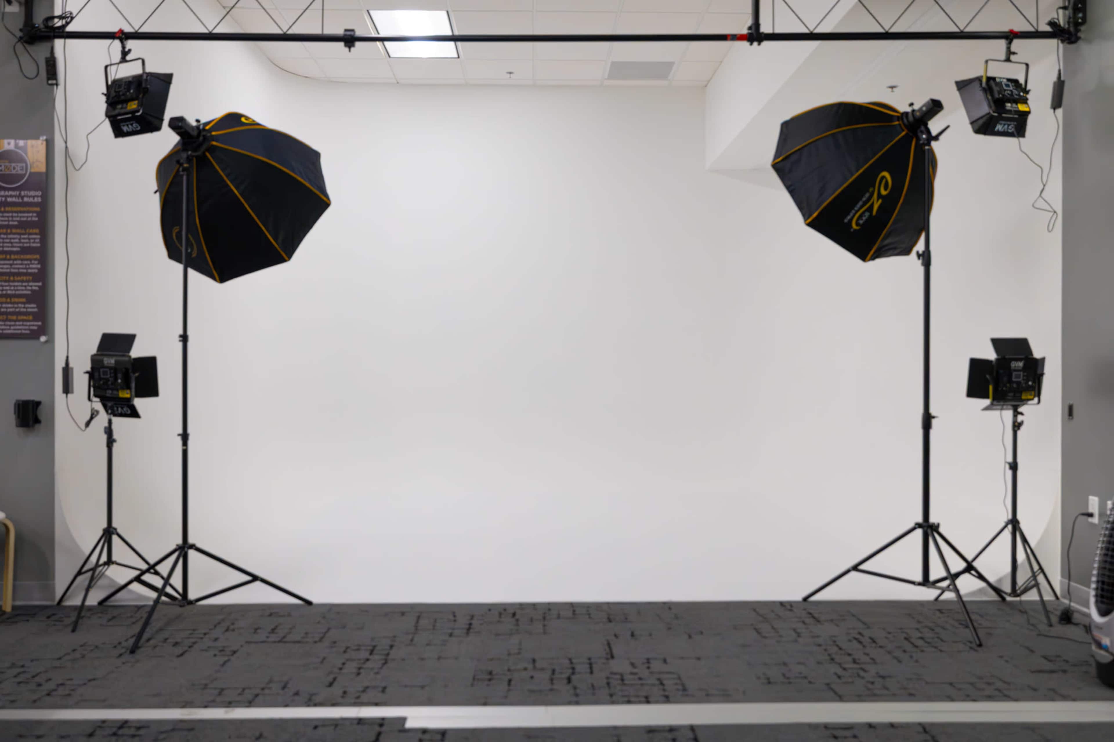 A photo studio setup features two large softbox lights on tripods, positioned in front of a seamless white backdrop.
